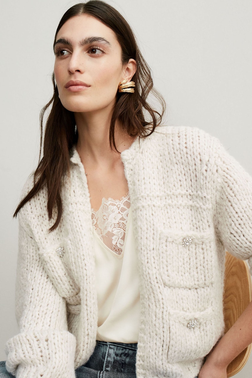 Stylish women's cardigan: A woman in a cozy cream cardigan with pockets, paired with a delicate top.