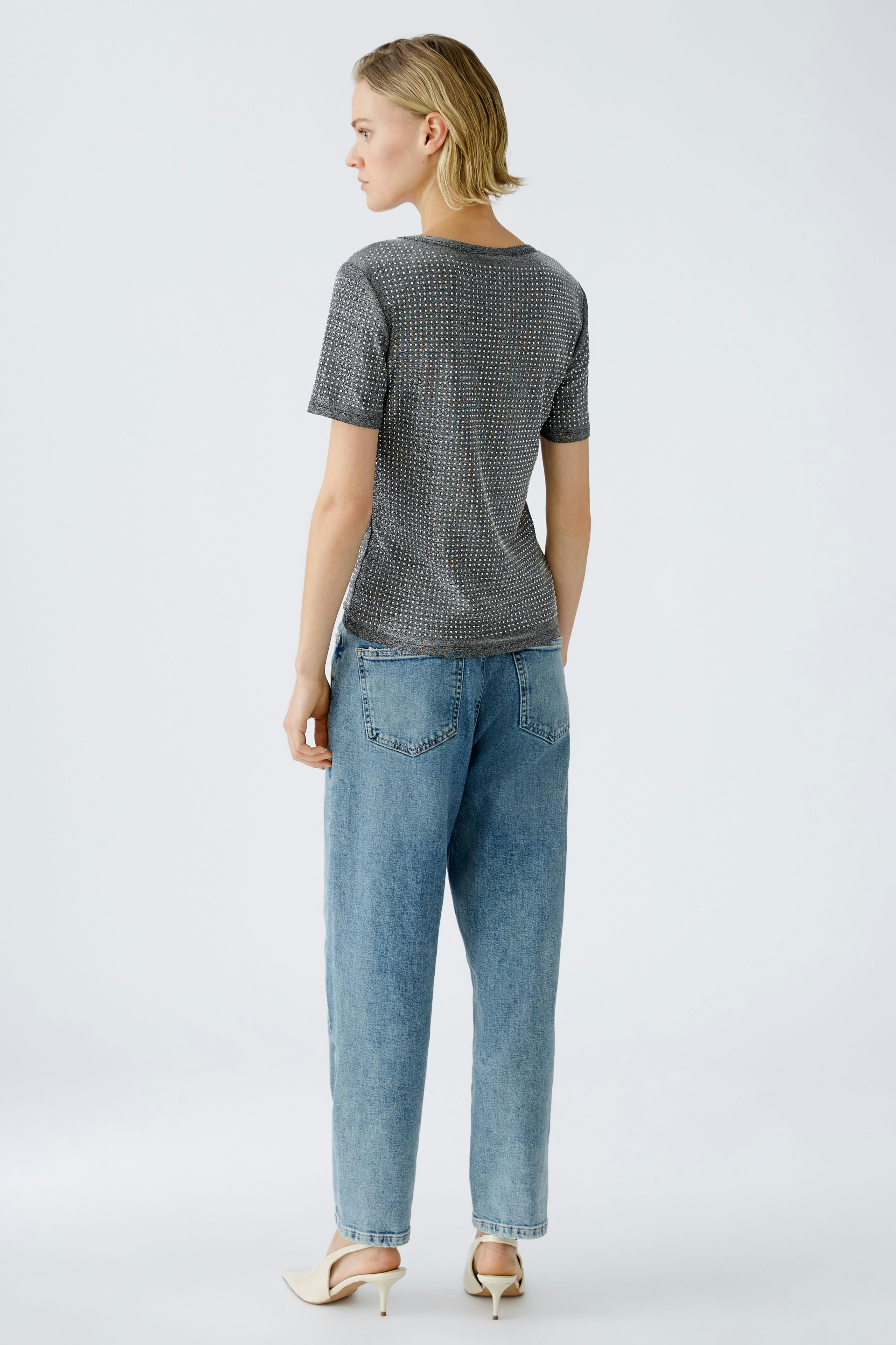 Damen-T-Shirt: Frau trägt ein graues, gemustertes T-Shirt mit kurzen Ärmeln und lässigen Jeans.