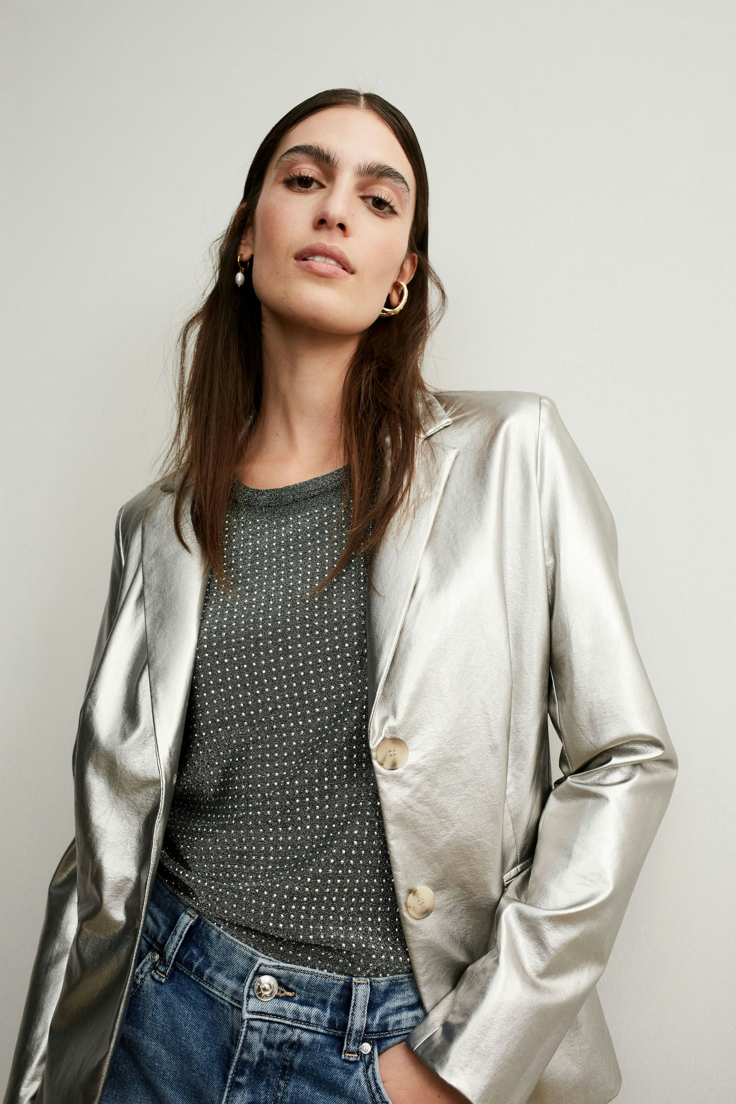 Elegantes Damen-T-Shirt: Frau in grauem T-Shirt mit feinen Punkten, kombiniert mit einem silbernen Blazer.