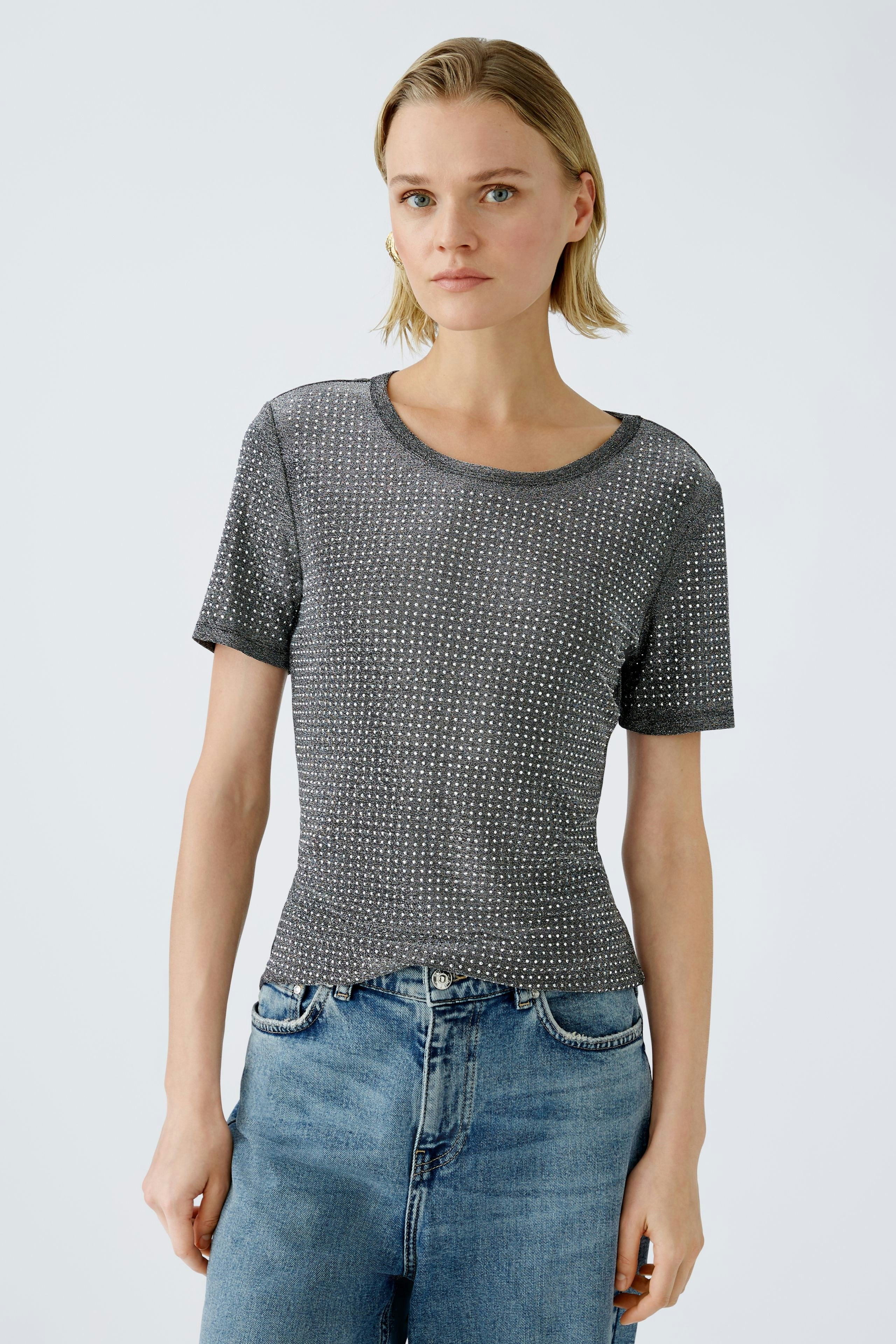 Damen-T-Shirt: Junge Frau trägt ein graues, gemustertes T-Shirt mit kurzen Ärmeln und lässigen Jeans.