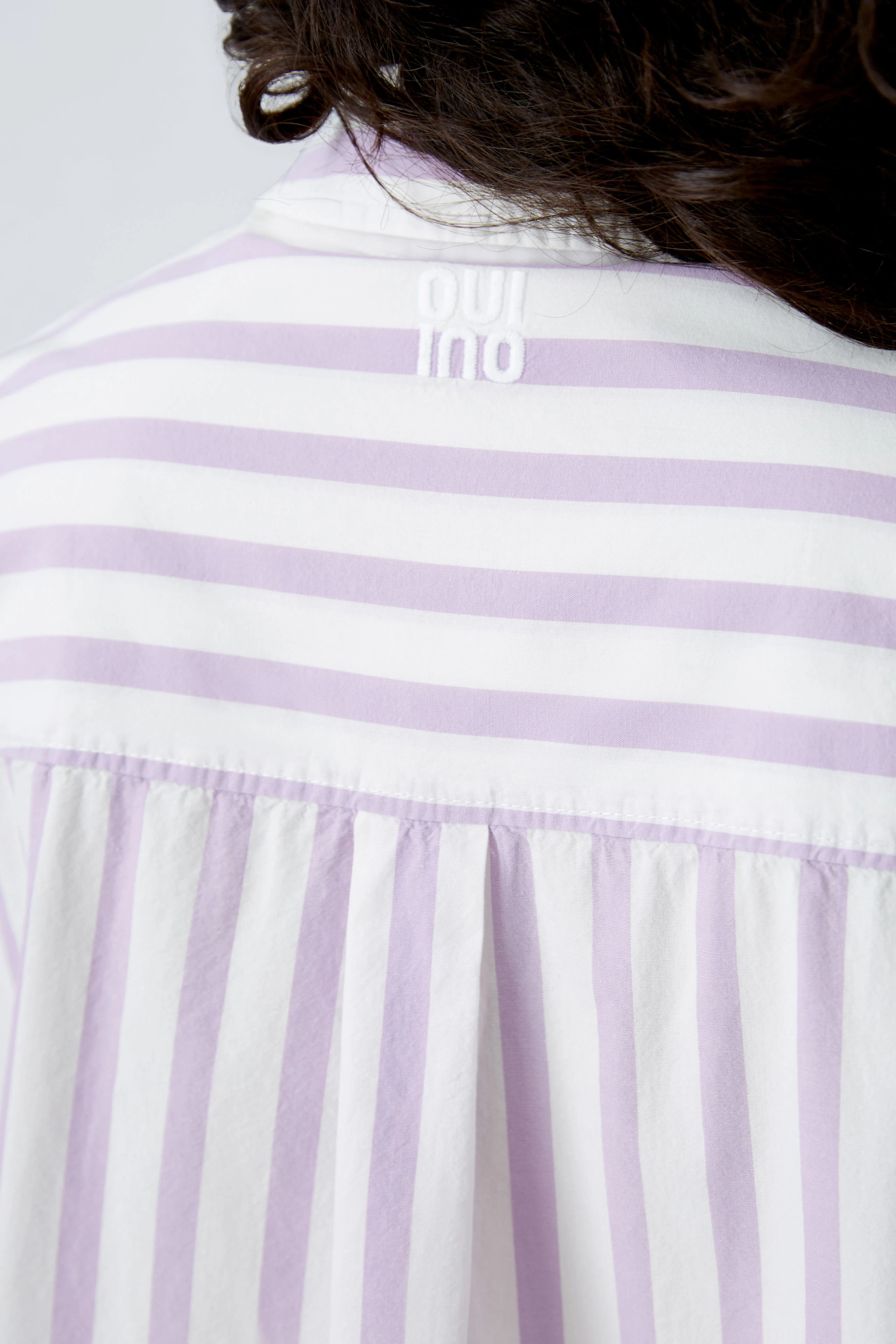 Lässige Damen-Bluse mit lila-weißen Streifen und feinem Rücken-Detail für einen modernen Look.