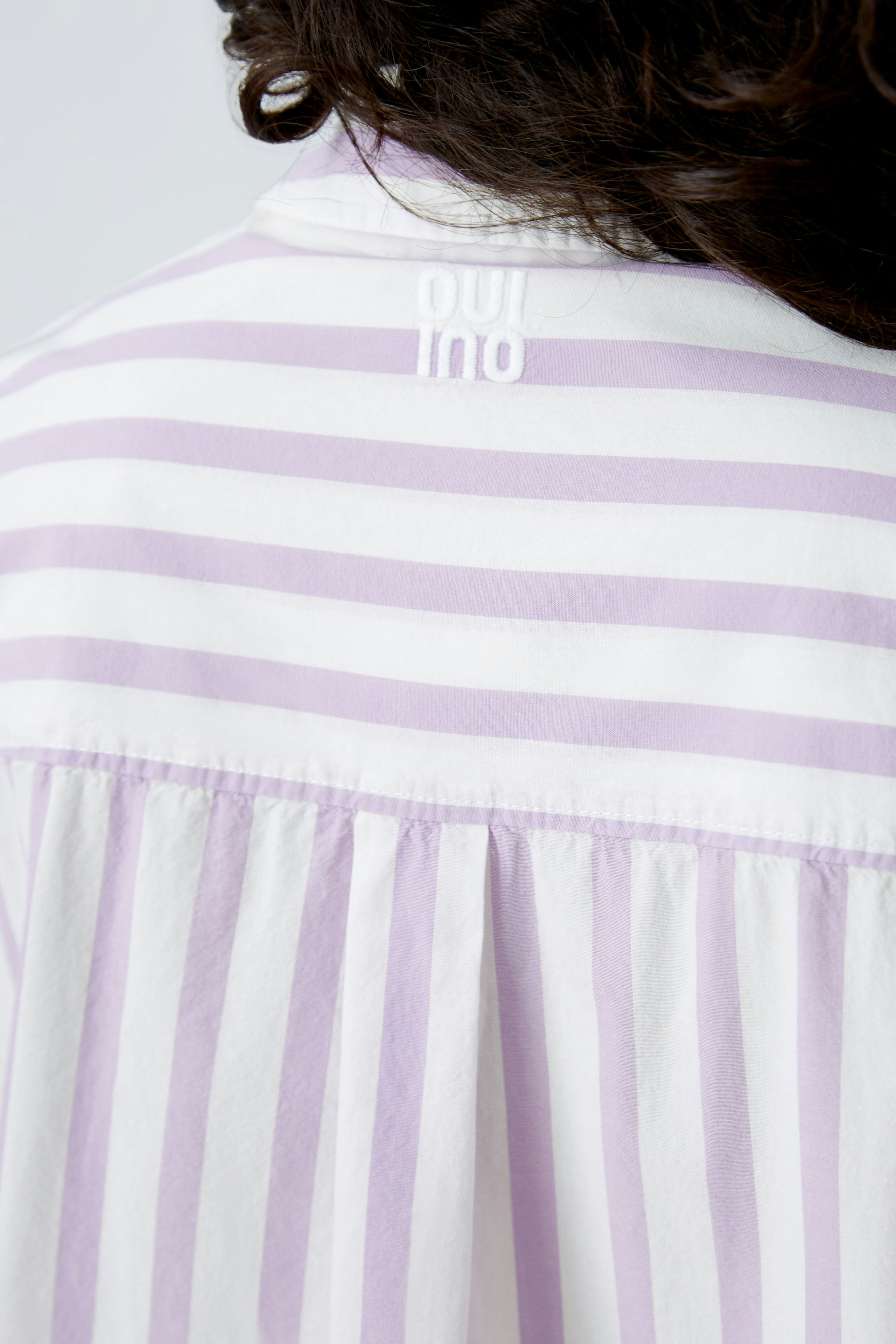 Stylish blouse: Woman in a light purple striped blouse with a relaxed fit and elegant details.