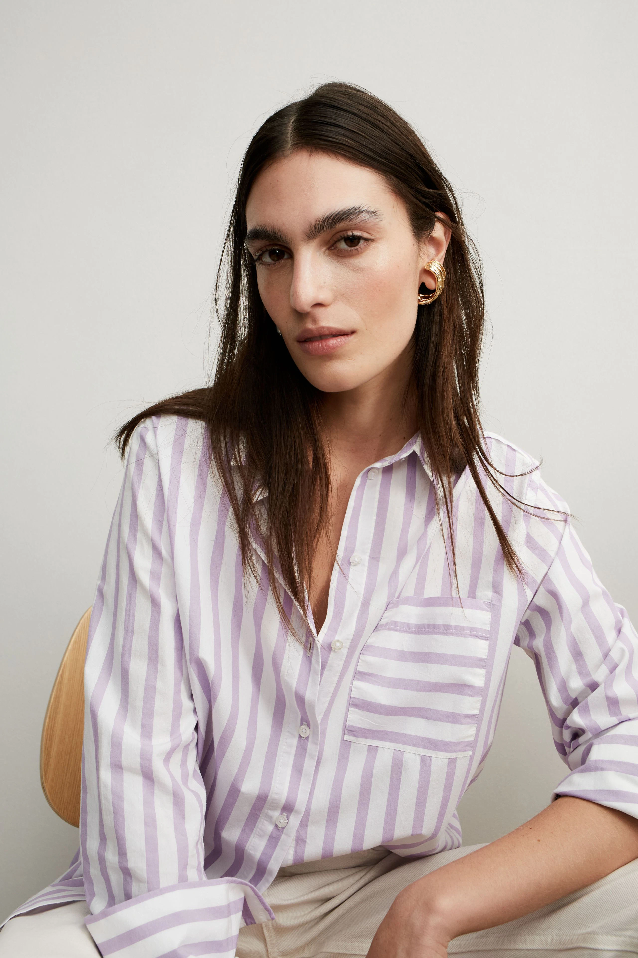 Elegante Damen-Bluse: Frau in lila-gestreifter Bluse mit Brusttasche, lässig und stilvoll.