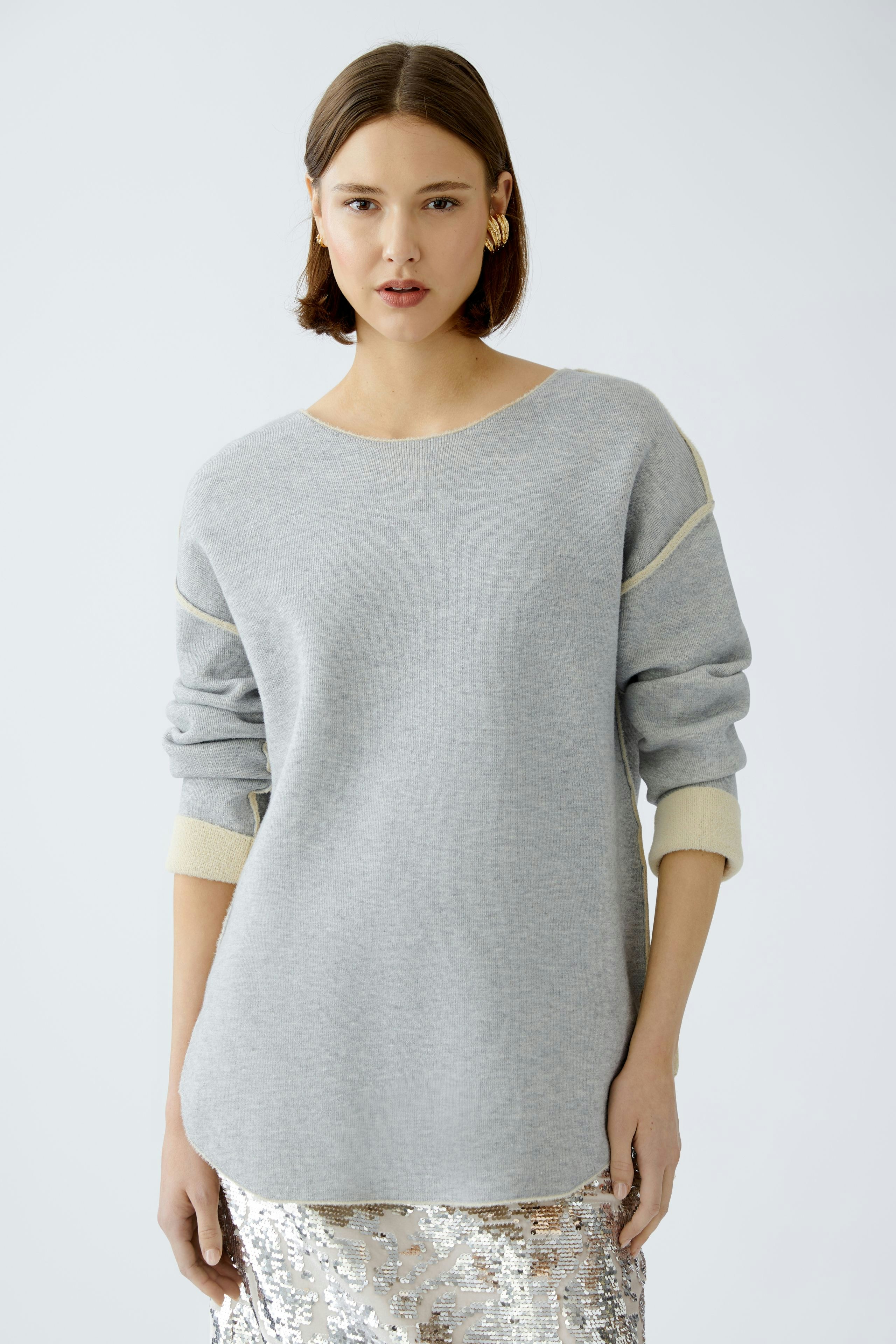Modern women's pullover: A woman in a light gray pullover with contrasting cuffs, exuding casual elegance.