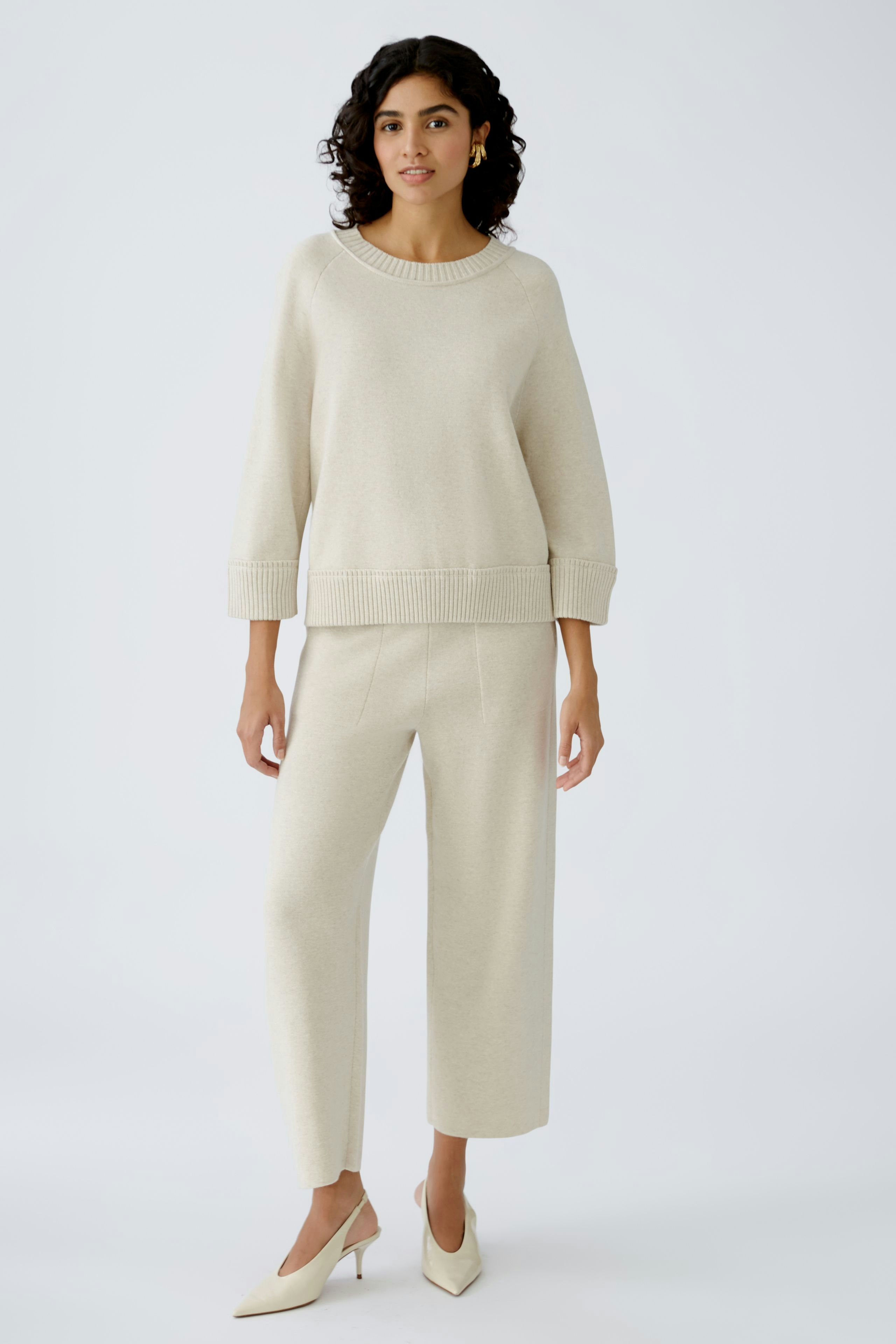 Damen-Pullover: Frau in hellem, lässigem Strickpullover mit weitem Schnitt und eleganten Hosen.
