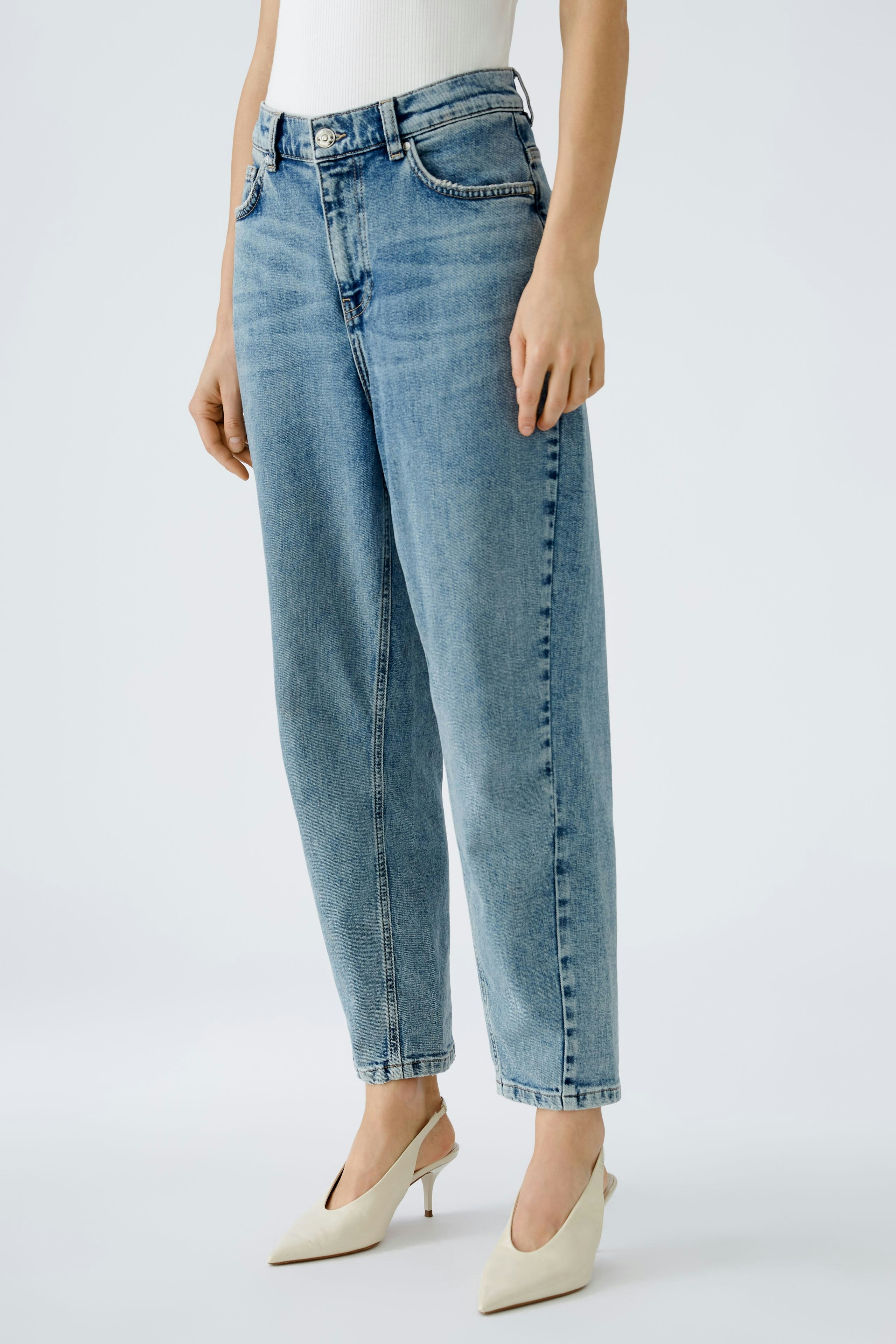 Bequeme 5-Pocket Hose: Frau trägt lässige, hellblaue Jeans mit weitem Schnitt und eleganten Schuhen.