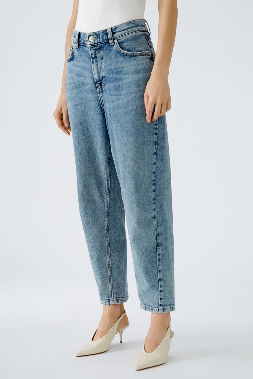 Stylish 5-pocket trousers: Woman in light blue jeans, paired with elegant heels, showcasing a modern look.