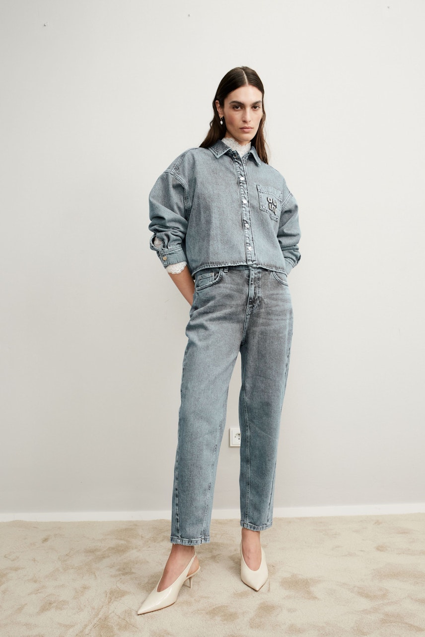 Stylish 5-pocket trousers: A confident woman in light denim pants, paired with a matching shirt.