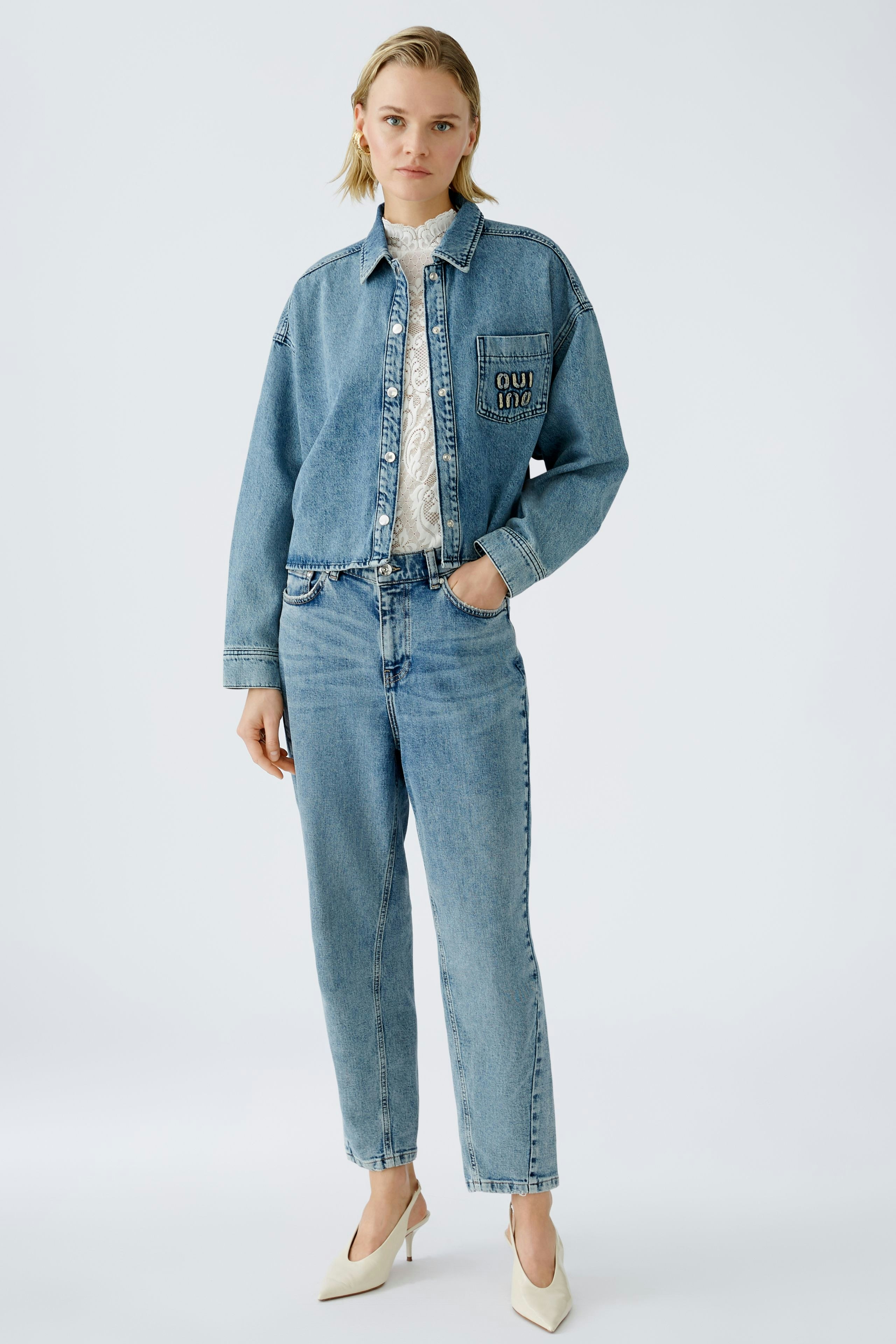 Moderne 5-Pocket Hose: Junge Frau in lässiger Jeans mit passender Jacke und eleganten Schuhen.