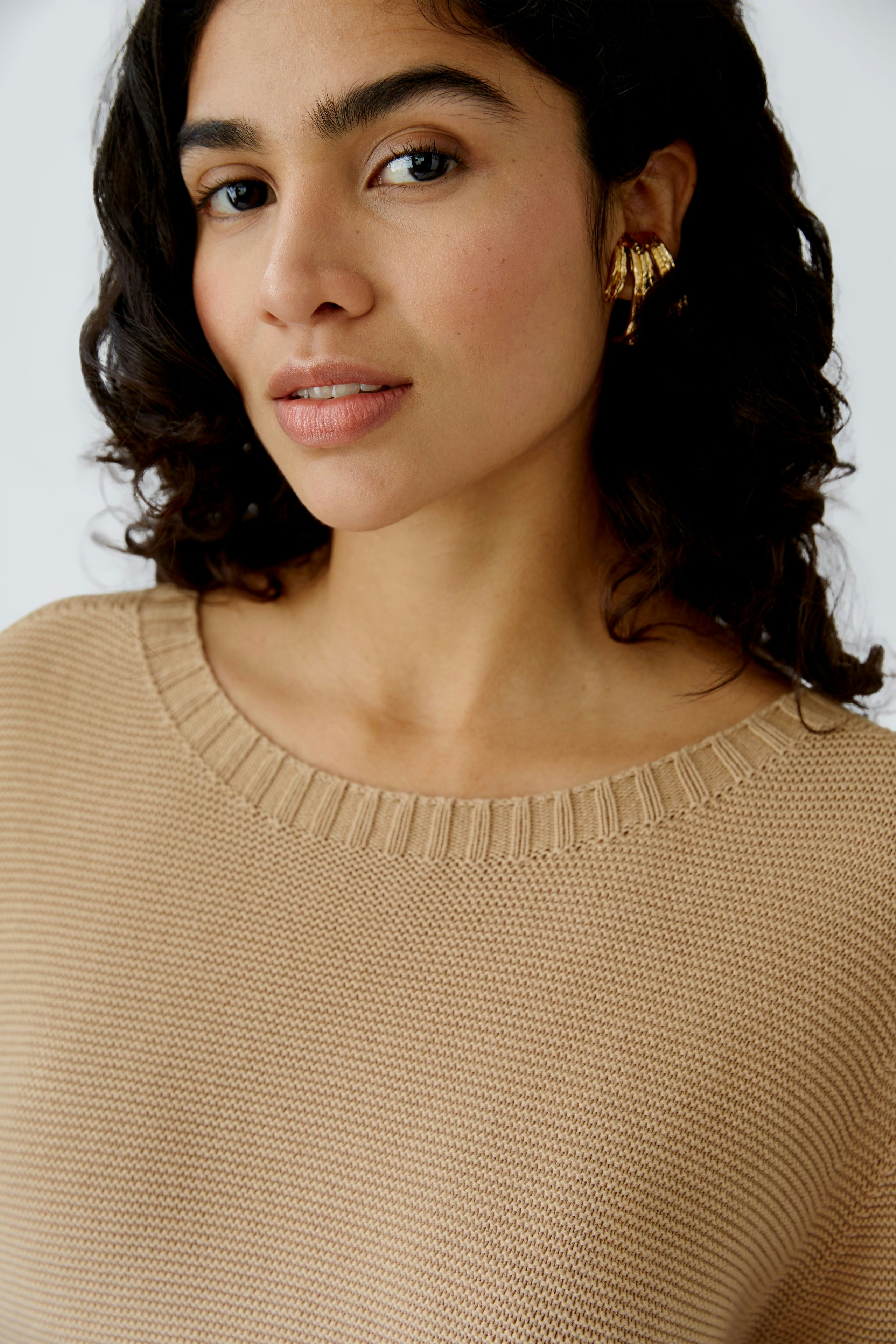 Modern women's pullover: A woman in a light beige pullover with a relaxed fit and elegant style.