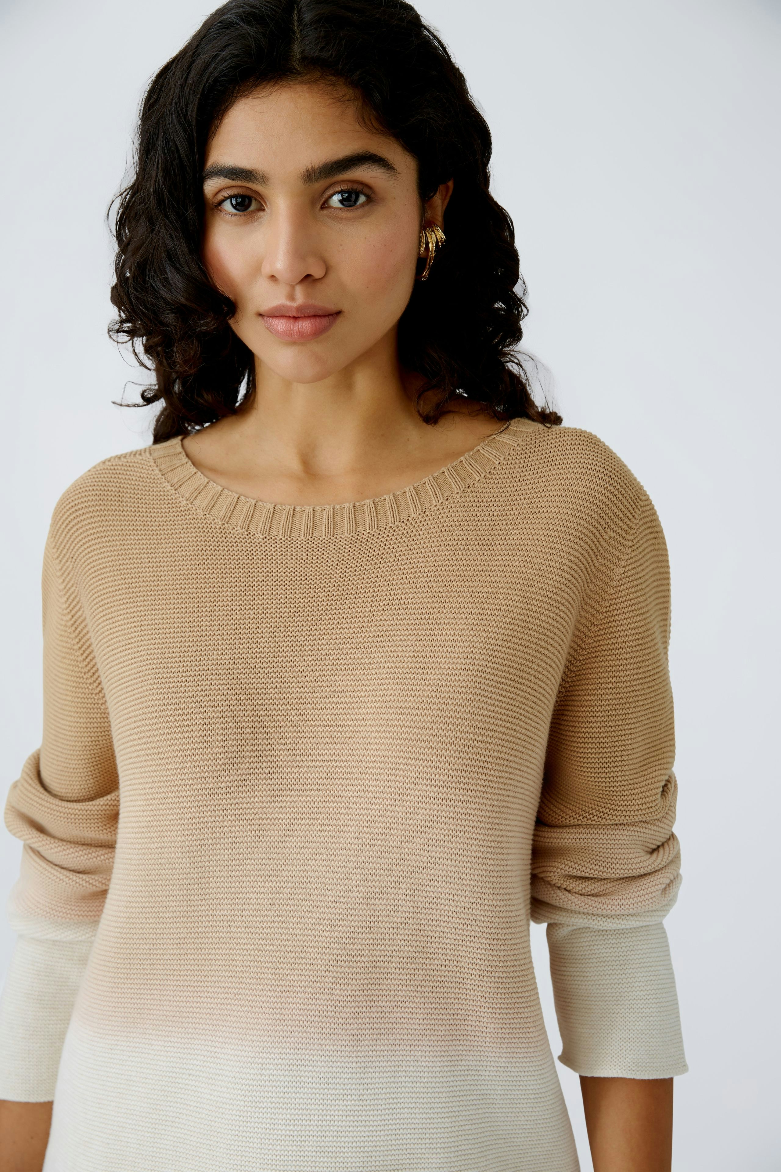 Modern women's pullover: A woman in a beige knit pullover with a stylish gradient design.