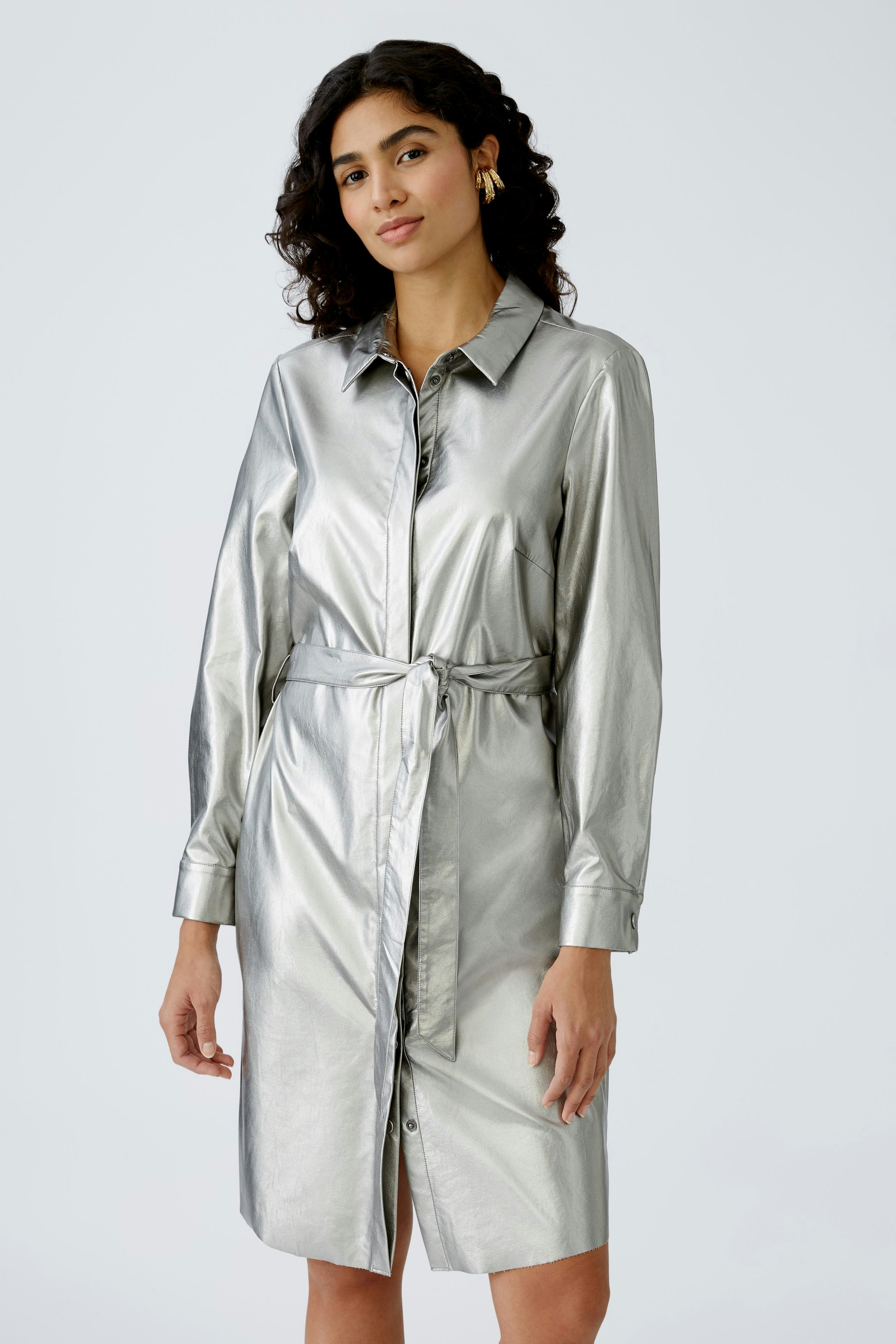 Shiny shirt dress: Woman in a metallic silver shirt dress with a belted waist, exuding modern elegance.