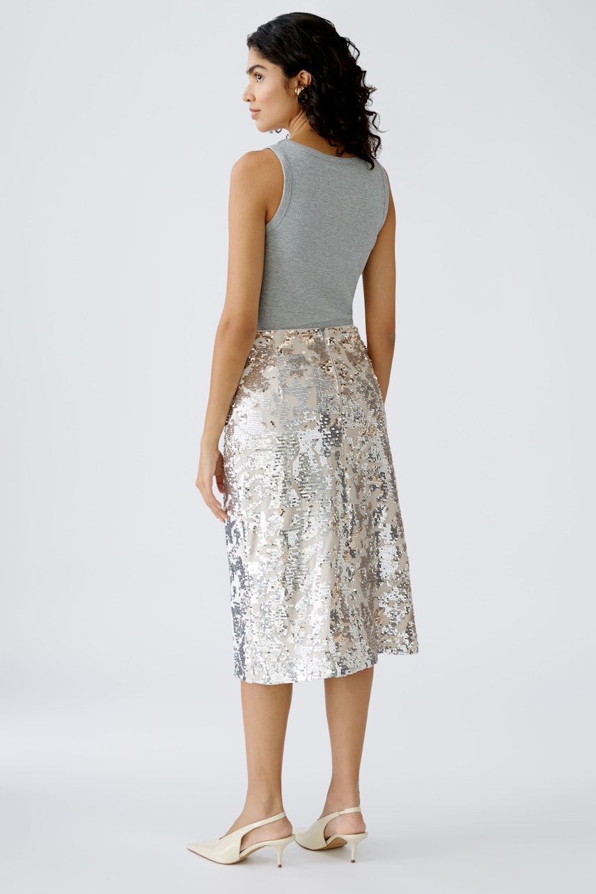 Elegant pencil skirt: Woman in a shimmering silver skirt, showcasing a stylish and modern design.