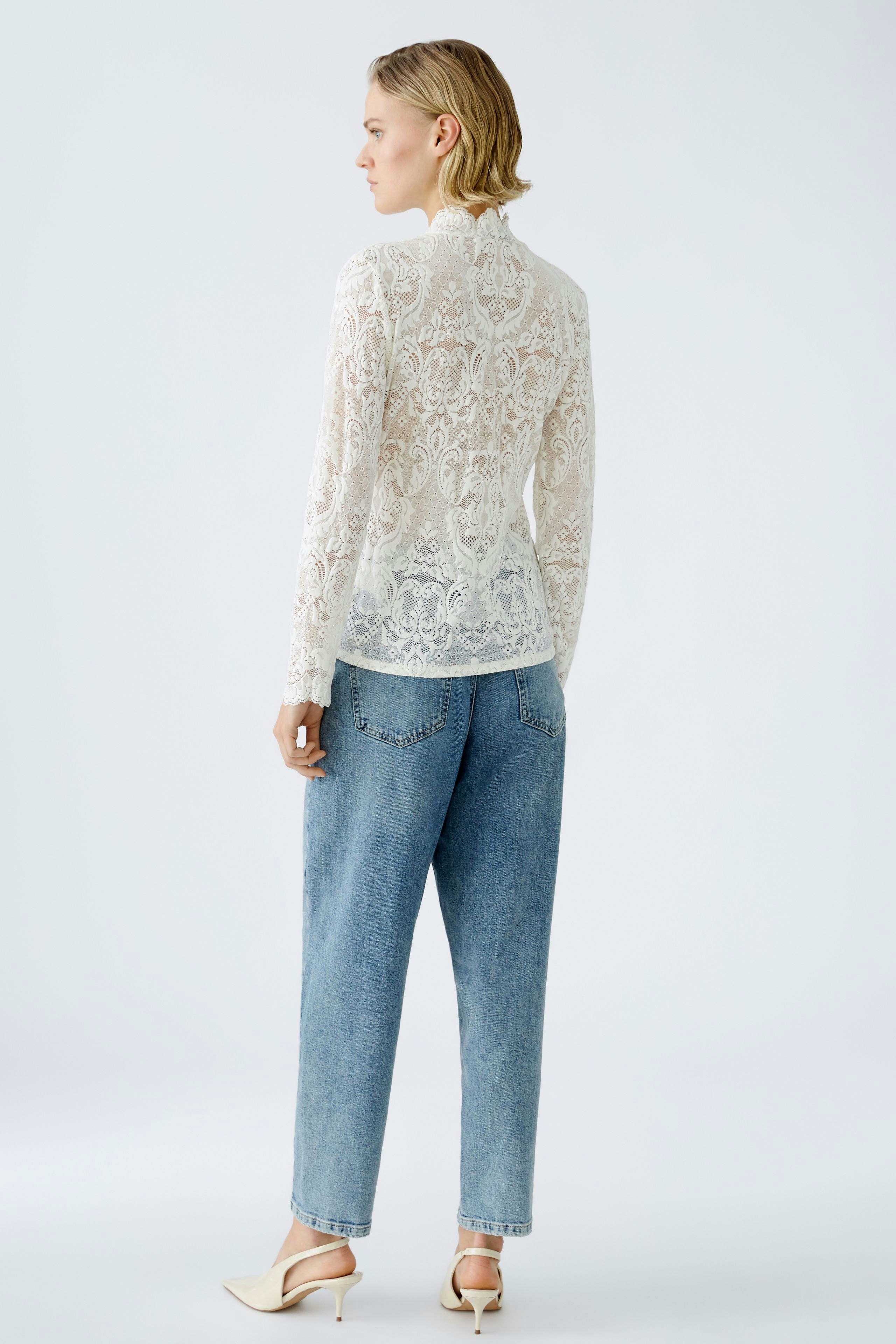 Elegant long-sleeve shirt: Woman in a delicate lace top paired with relaxed denim jeans.