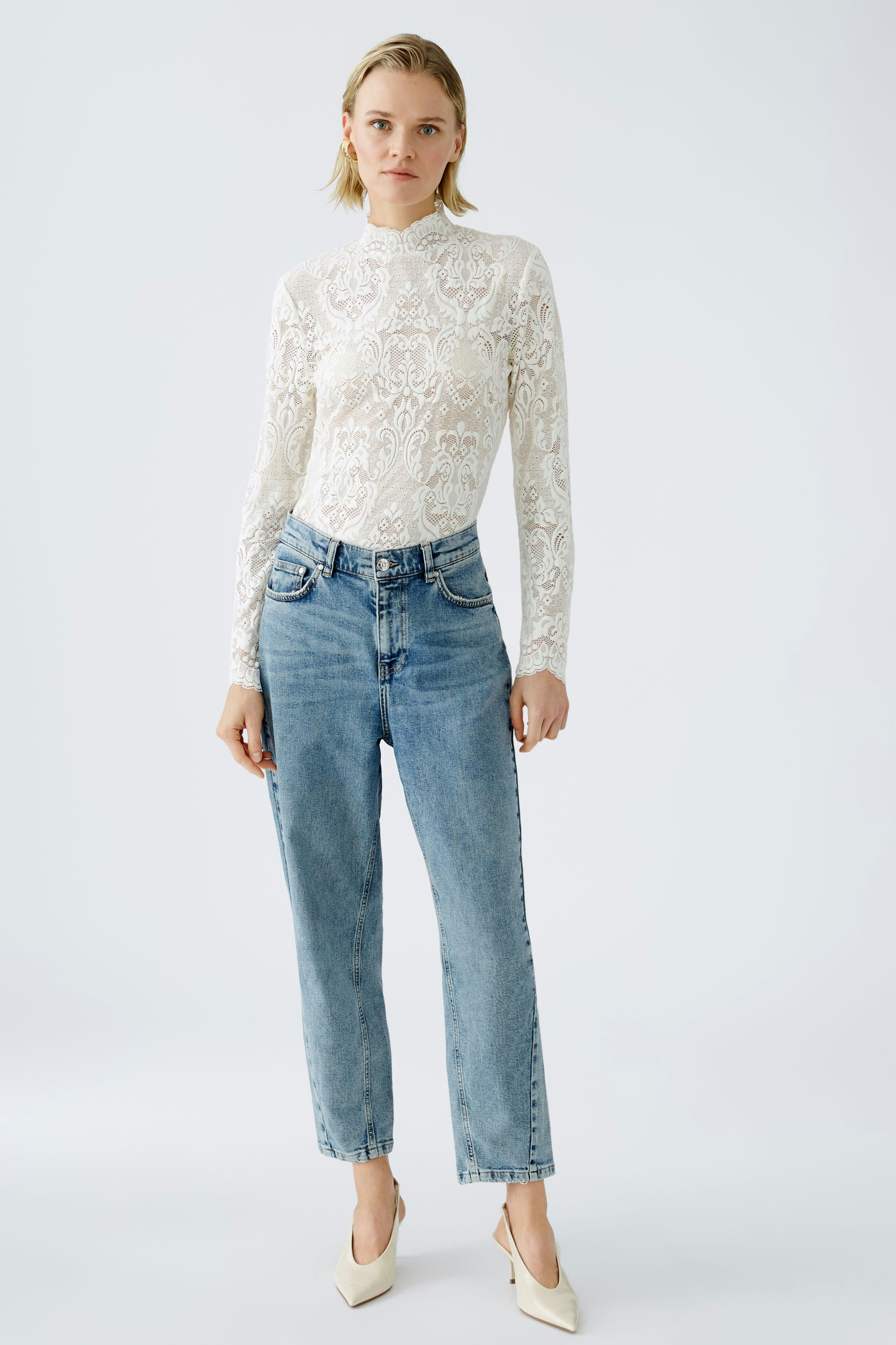 Elegant long-sleeve shirt: Woman in a white lace top paired with high-waisted jeans.