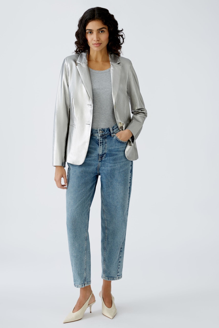 Stylish women's blazer: A woman in a silver blazer paired with jeans, exuding confidence.