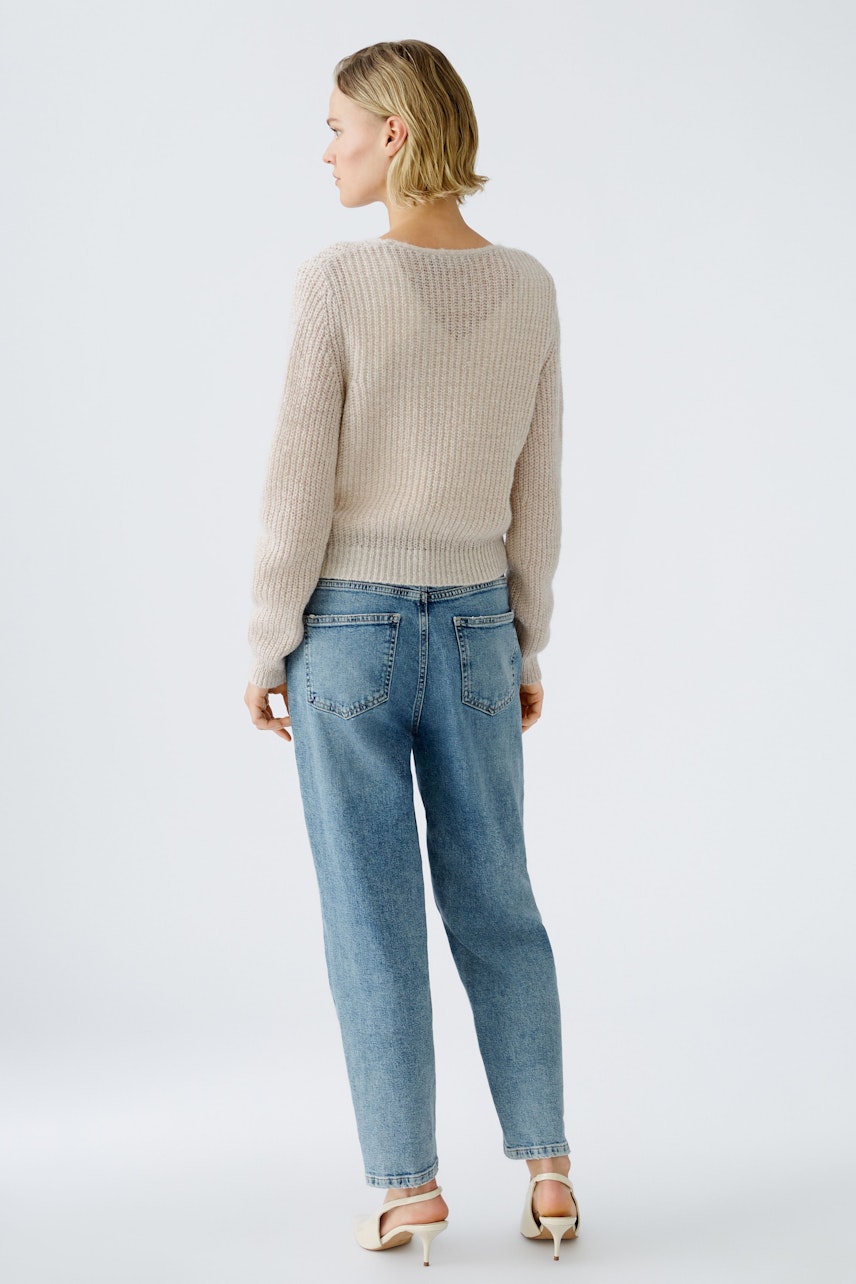 Stylish women's pullover: A woman in a light knit pullover and jeans, showcasing a relaxed look.