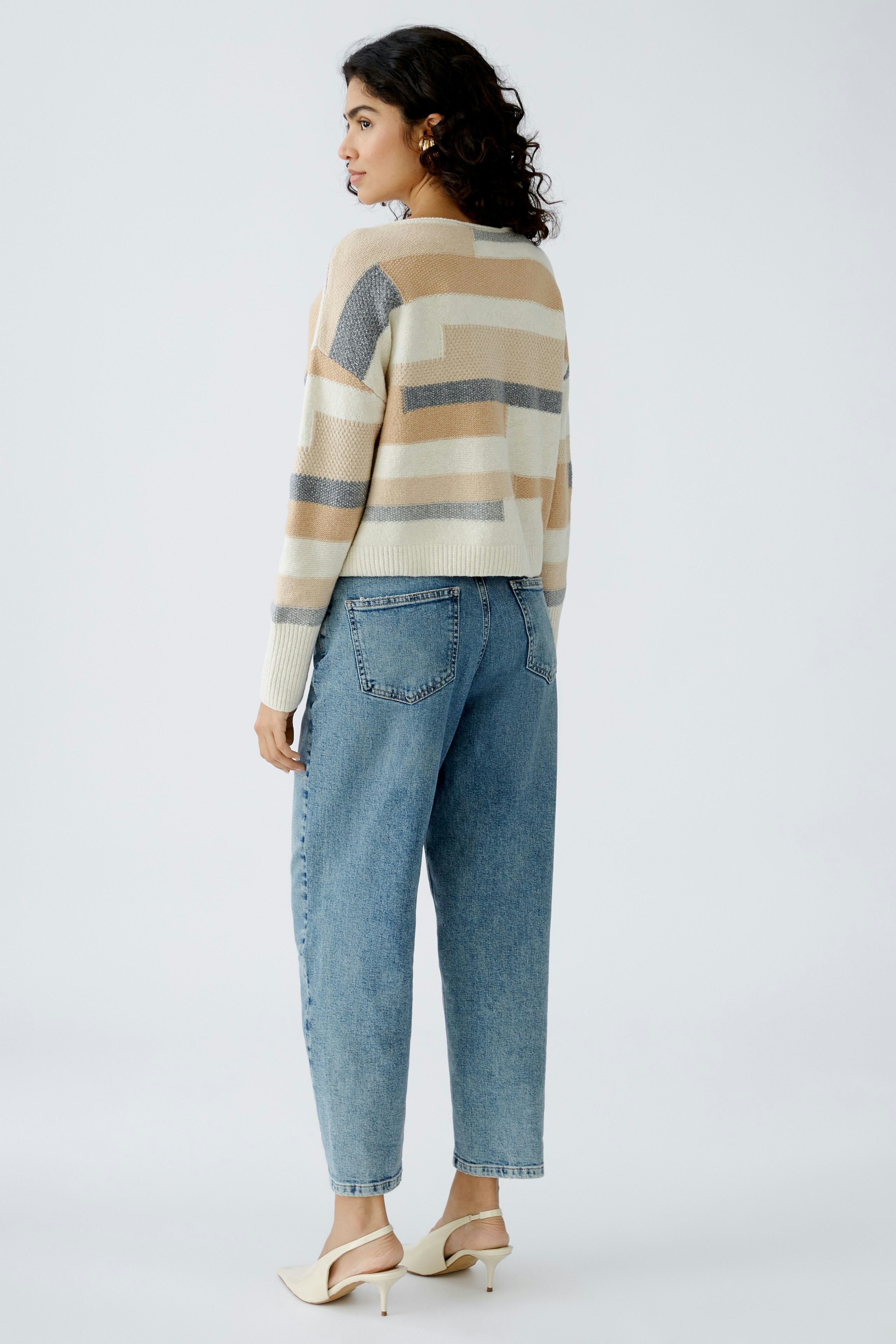 Stylish women's pullover: A woman in a striped, cropped pullover paired with high-waisted jeans.
