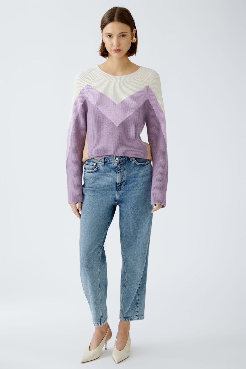 Stylish women's pullover: A woman in a purple and cream chevron-patterned pullover paired with jeans.