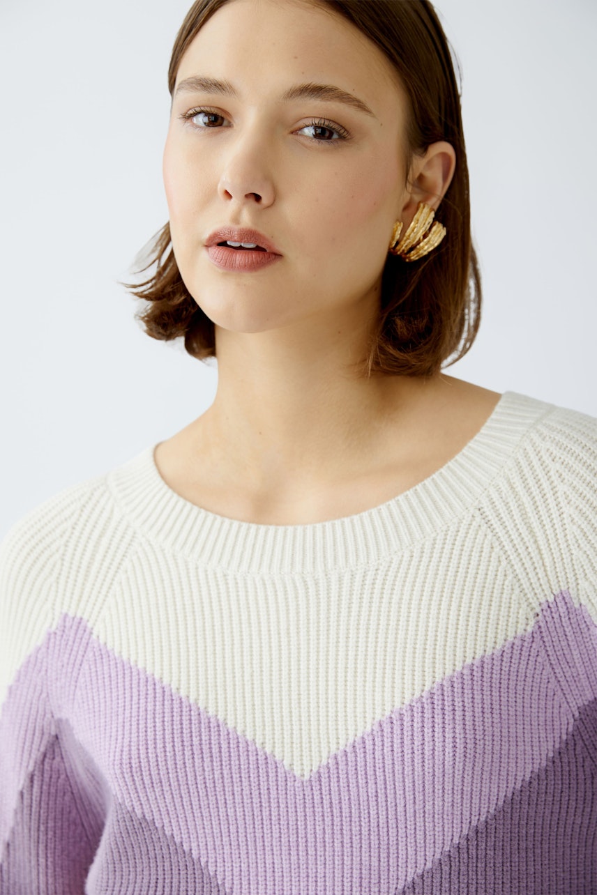 Stylish women's pullover: A woman in a cozy, chevron-patterned knit pullover in soft lavender and cream.