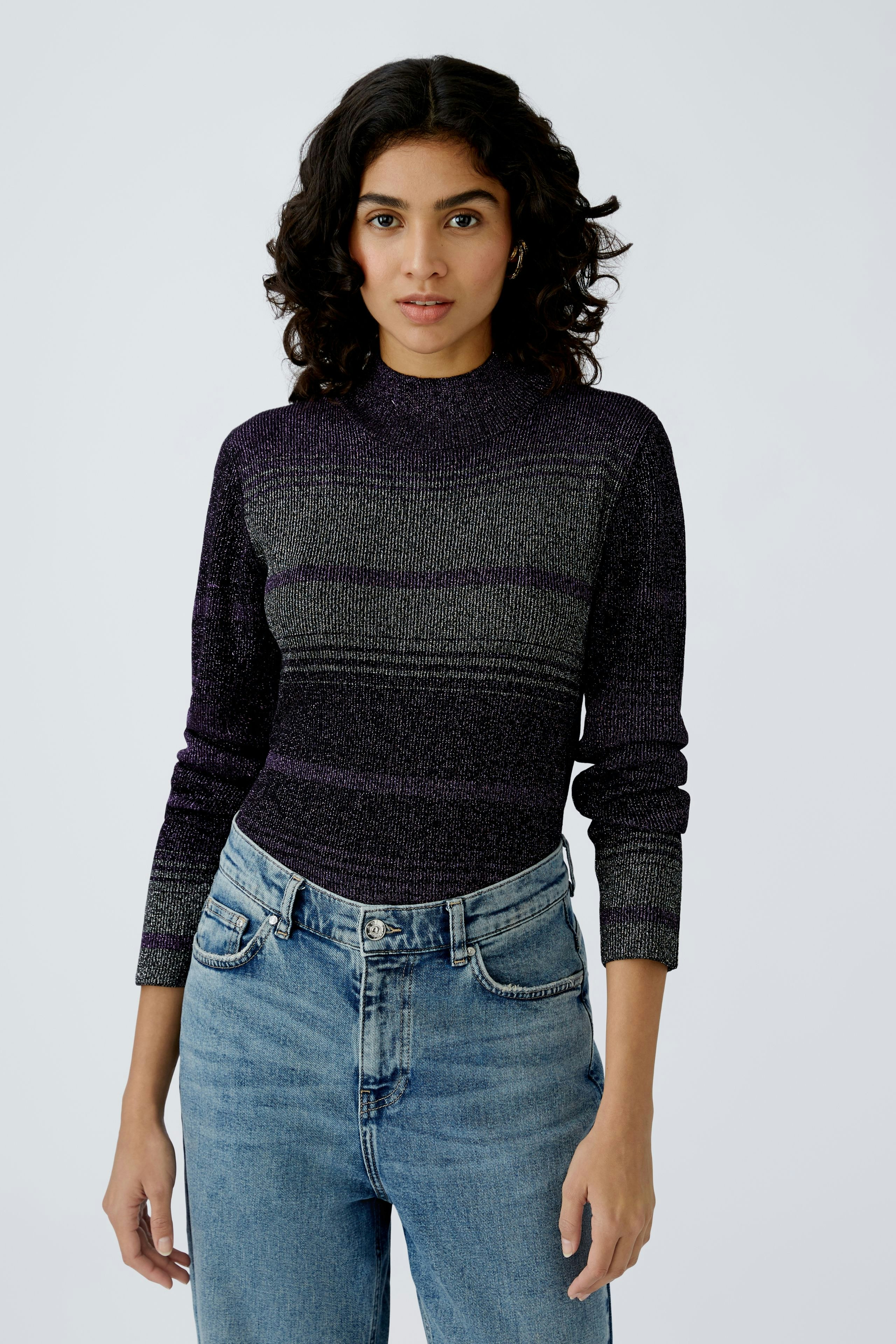 Stylish women's pullover: A woman in a purple striped pullover paired with high-waisted jeans.