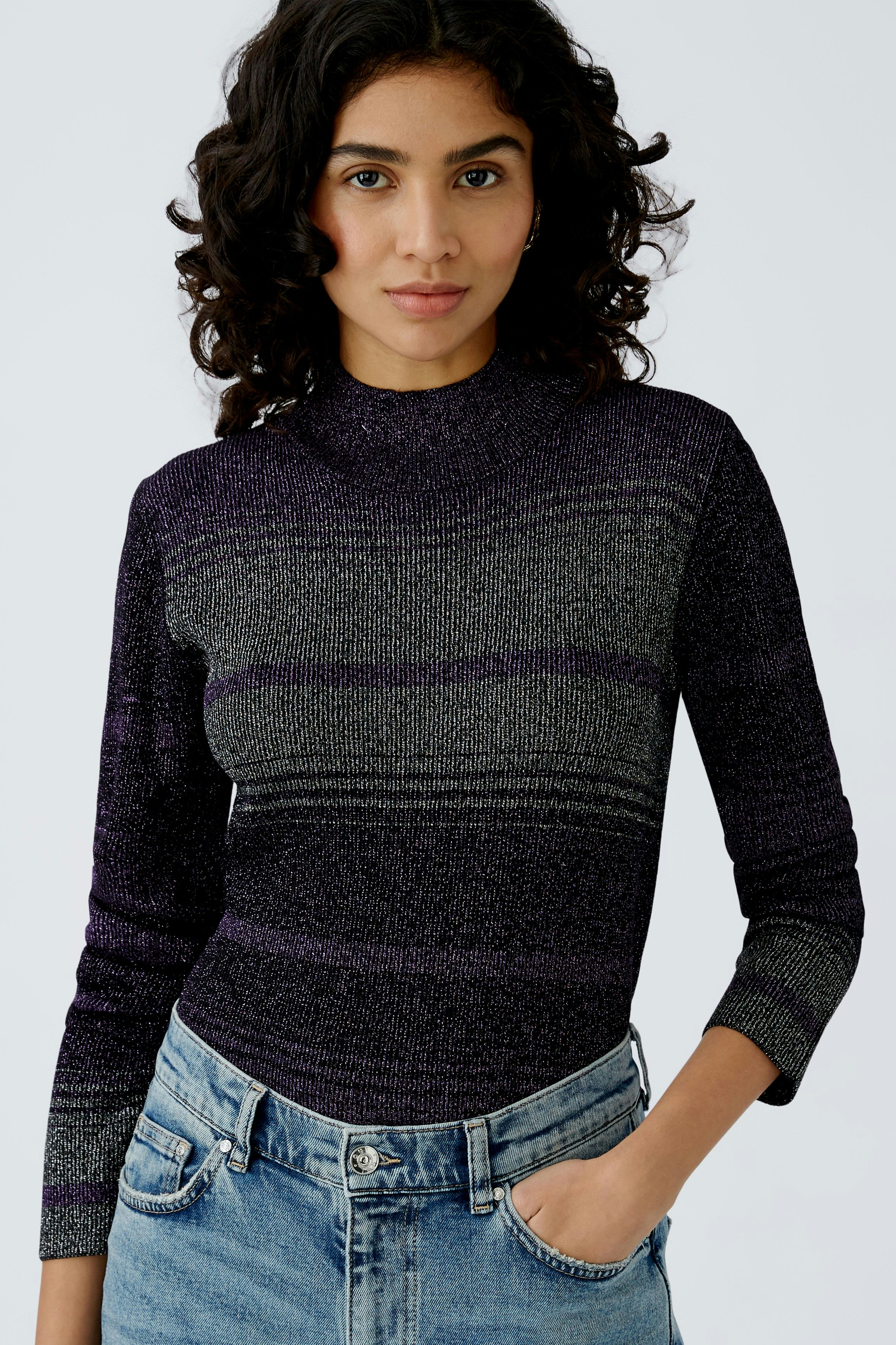 Stylish women's pullover: A woman in a fitted, striped pullover with a high neck and casual jeans.