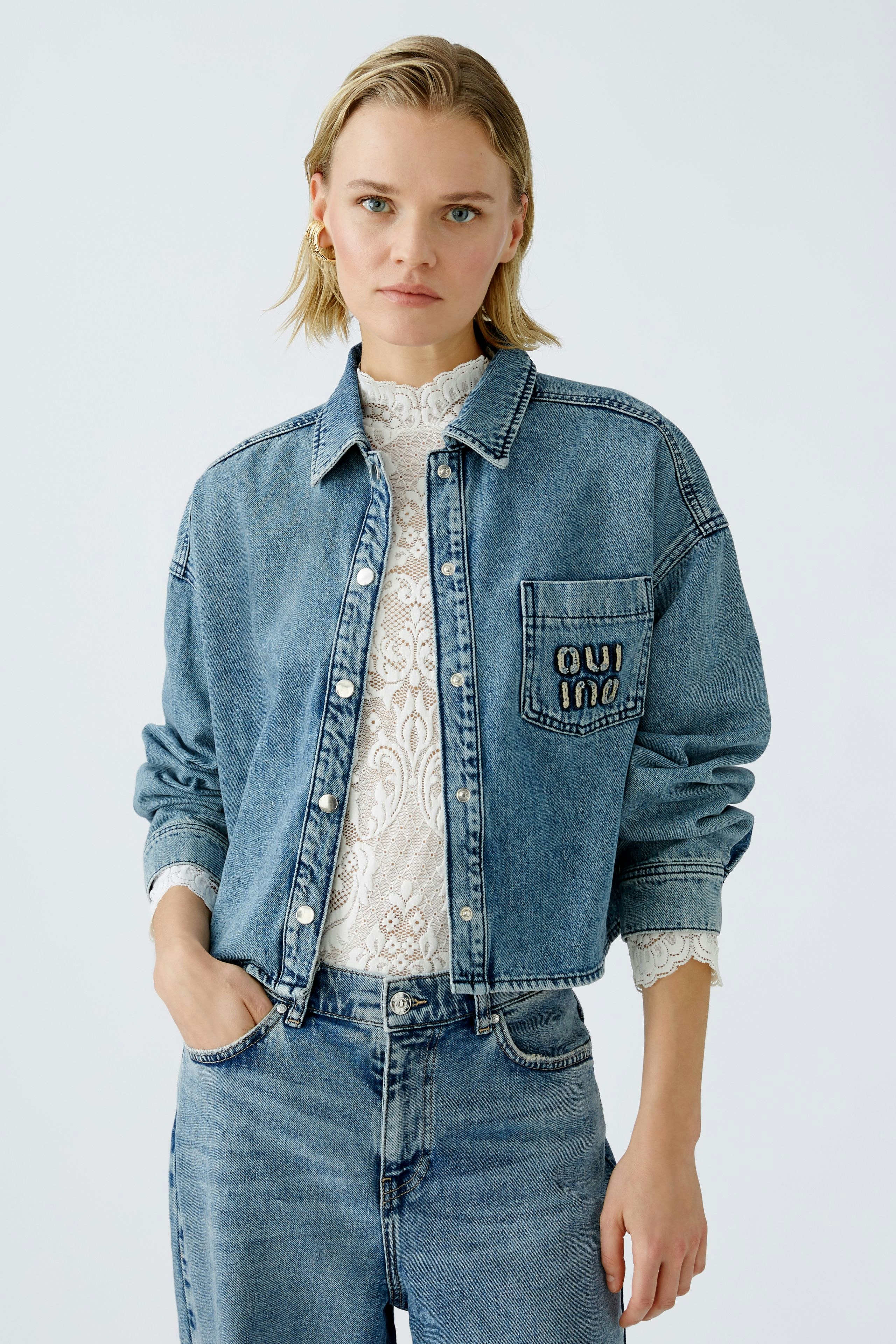 Stylish women's denim jacket: A woman in a classic blue jacket with a lace top, exuding casual elegance.