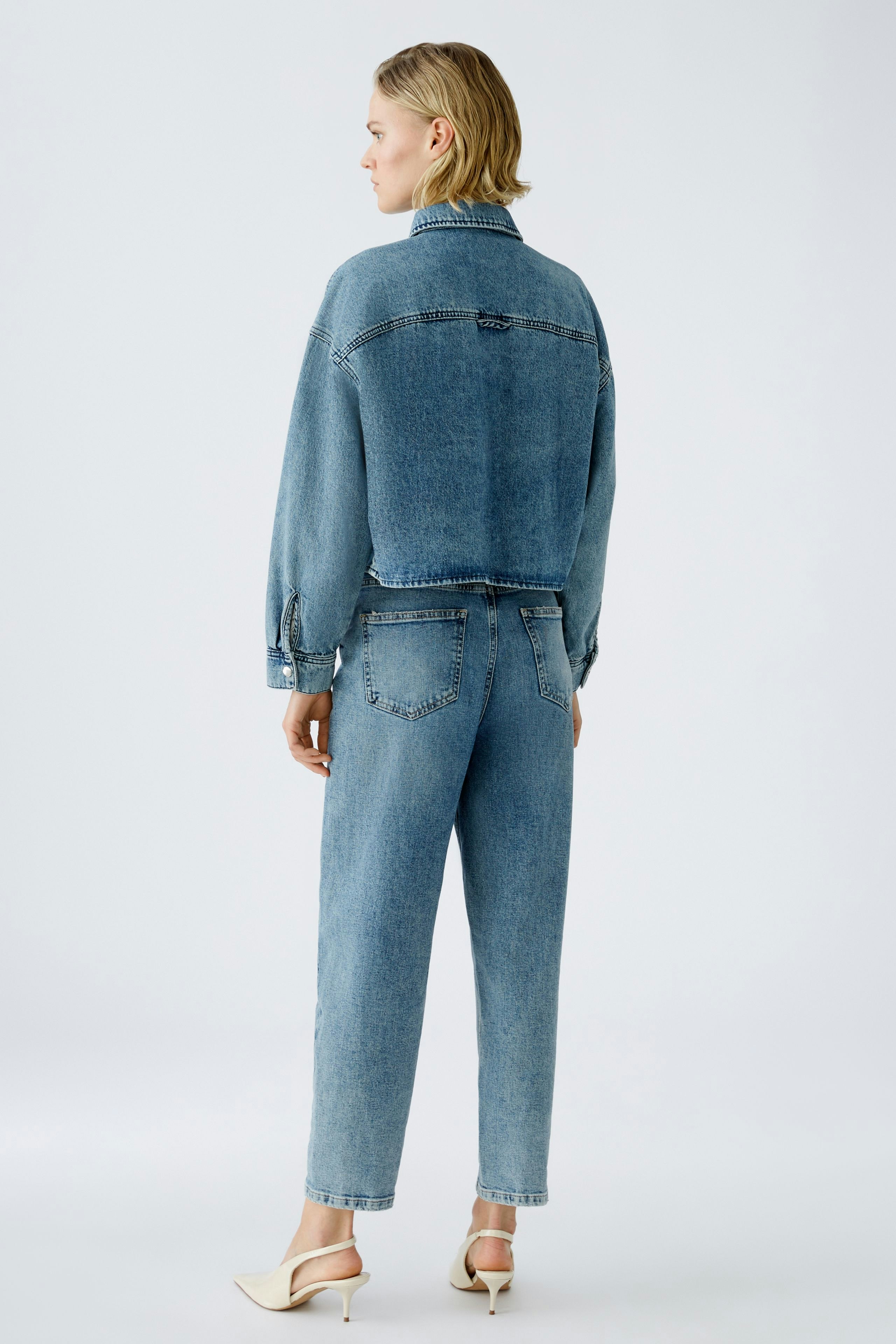 Stylish women's denim jacket: A woman in a light blue jacket with a relaxed fit, showcasing casual elegance.