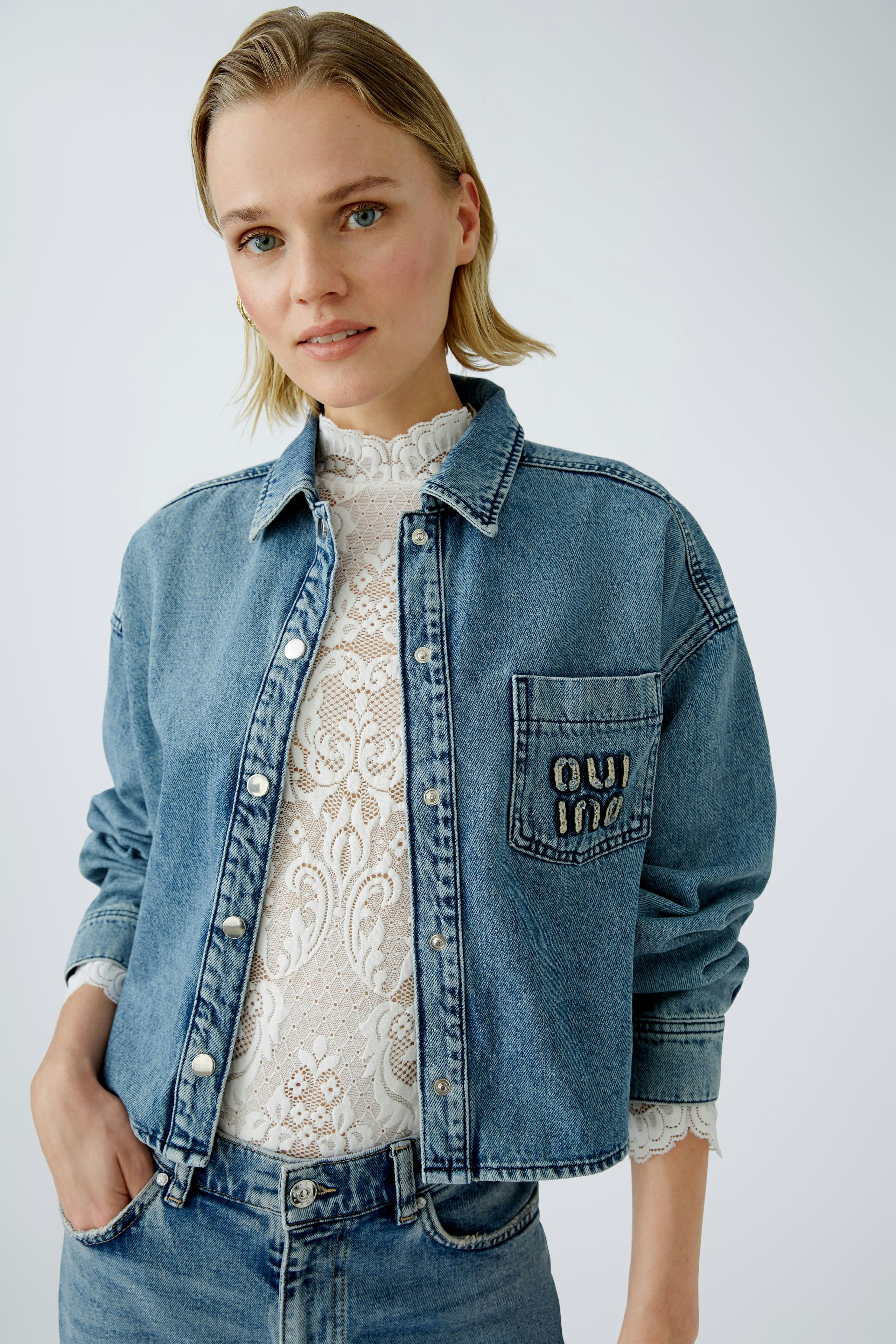 Stylish women's denim jacket: A woman in a classic blue denim jacket with a lace top.
