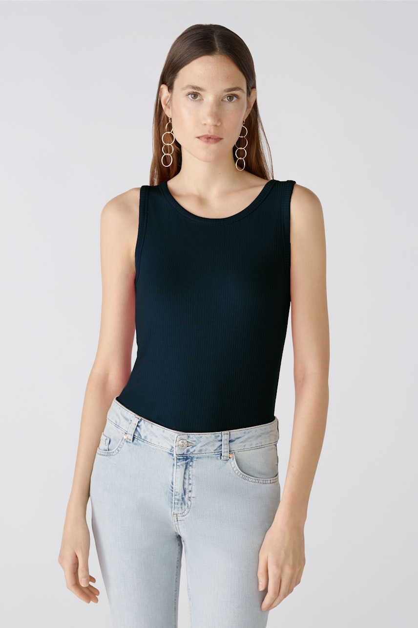 Sleek women's top: A woman in a fitted navy tank top paired with light jeans.