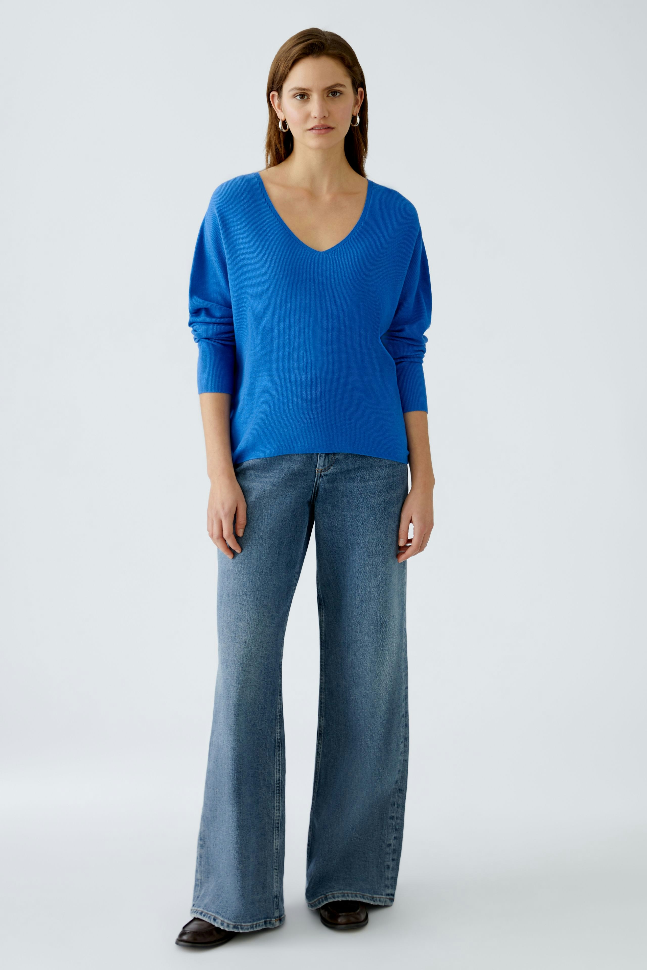 Stylish women's pullover: A woman in a vibrant blue pullover with a V-neck and relaxed fit.