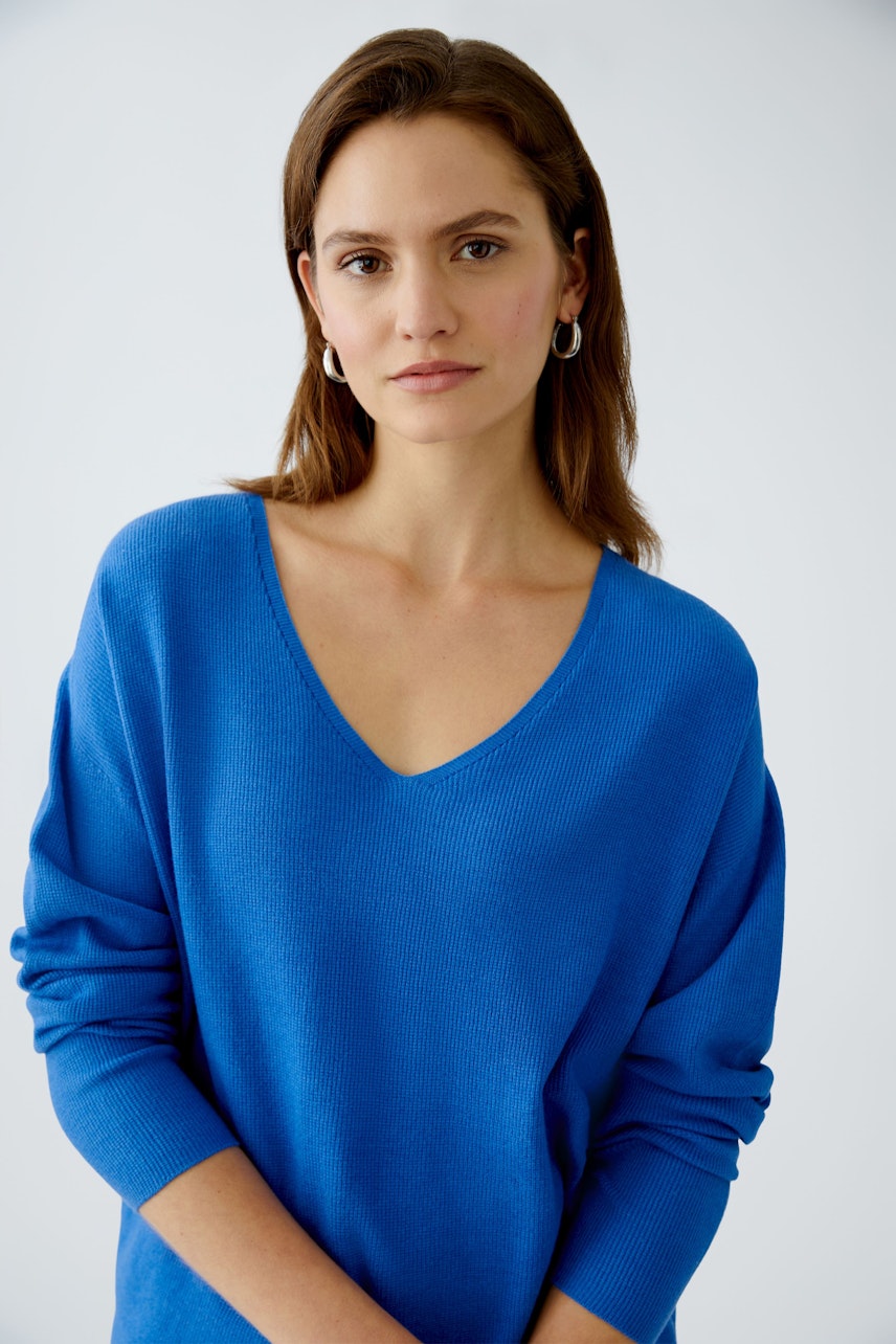 Damen-Pullover: Frau in blauem V-Ausschnitt-Pullover mit lässigem Schnitt und weichem Material.