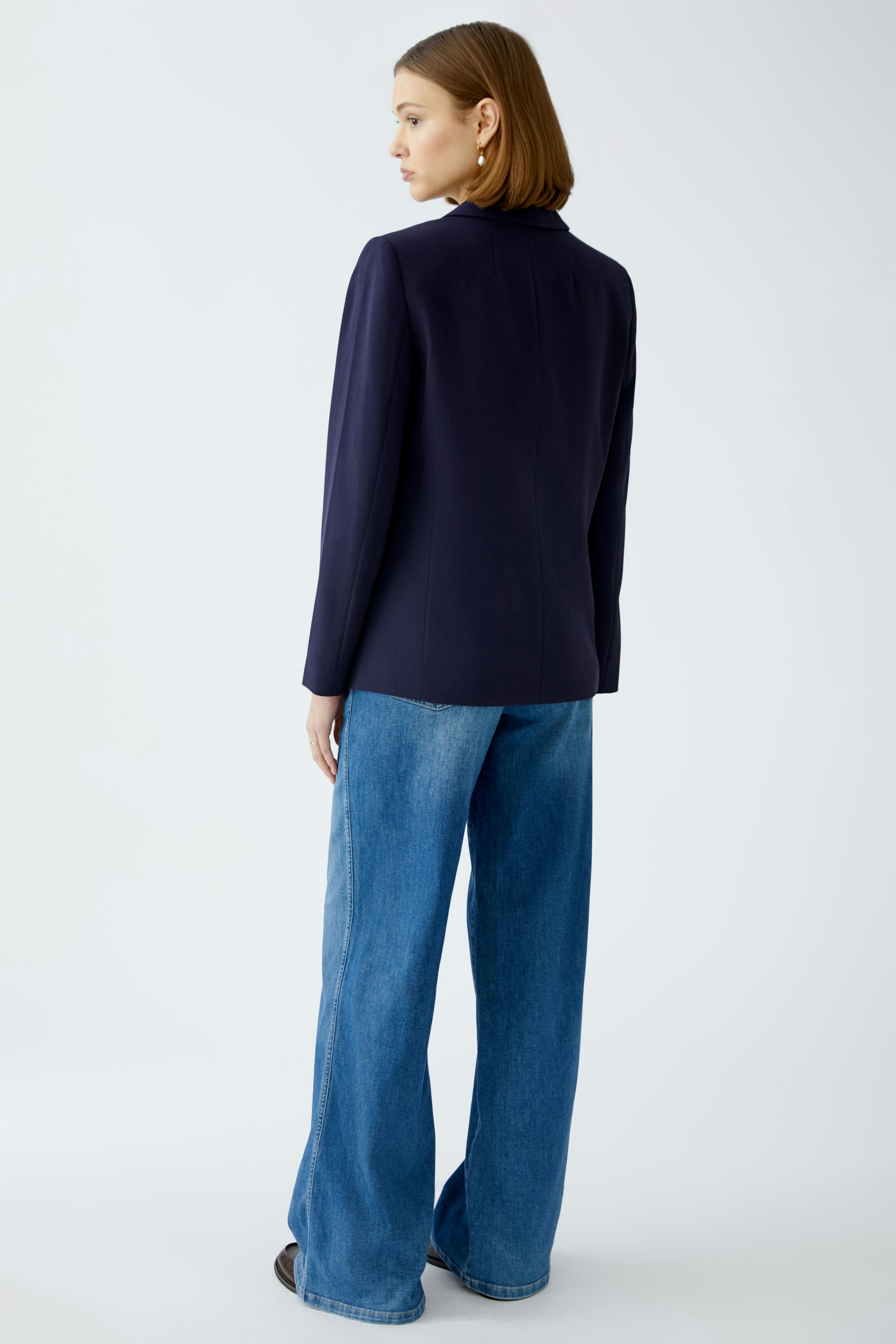 Eleganter Damen-Blazer: Frau in navyfarbenem Blazer mit schlichten Details und lässigen Jeans.