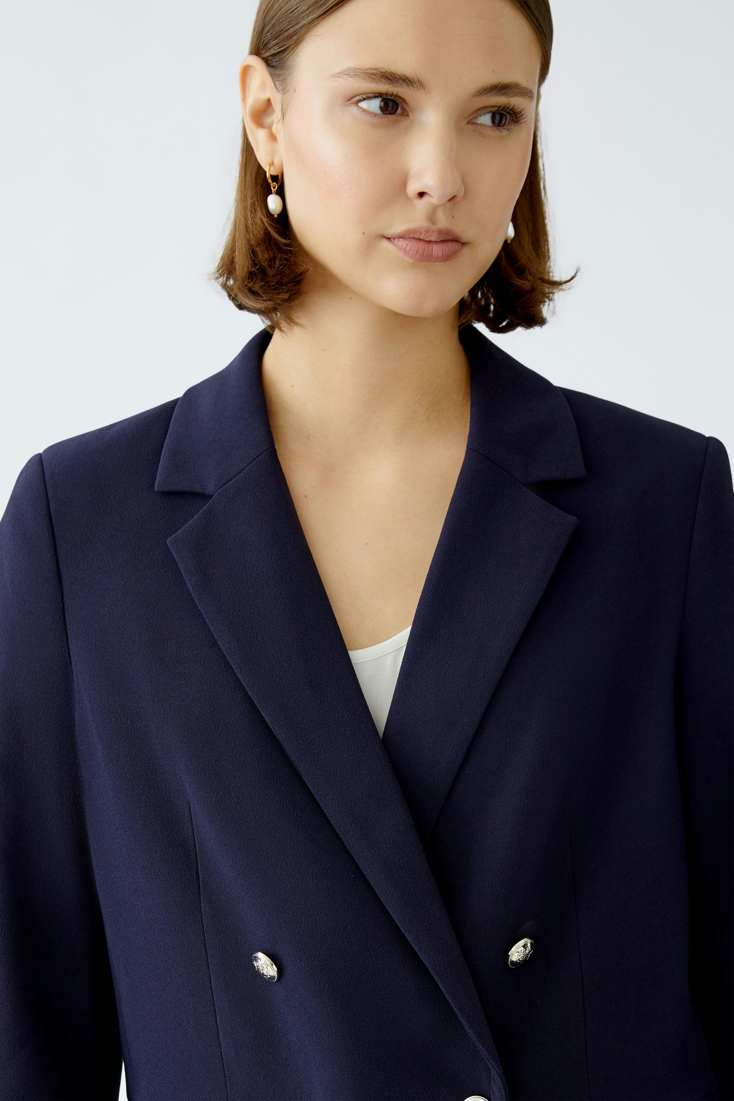 Eleganter Damen-Blazer: Frau in navyfarbenem Blazer mit doppelter Knopfleiste und klassischem Schnitt.