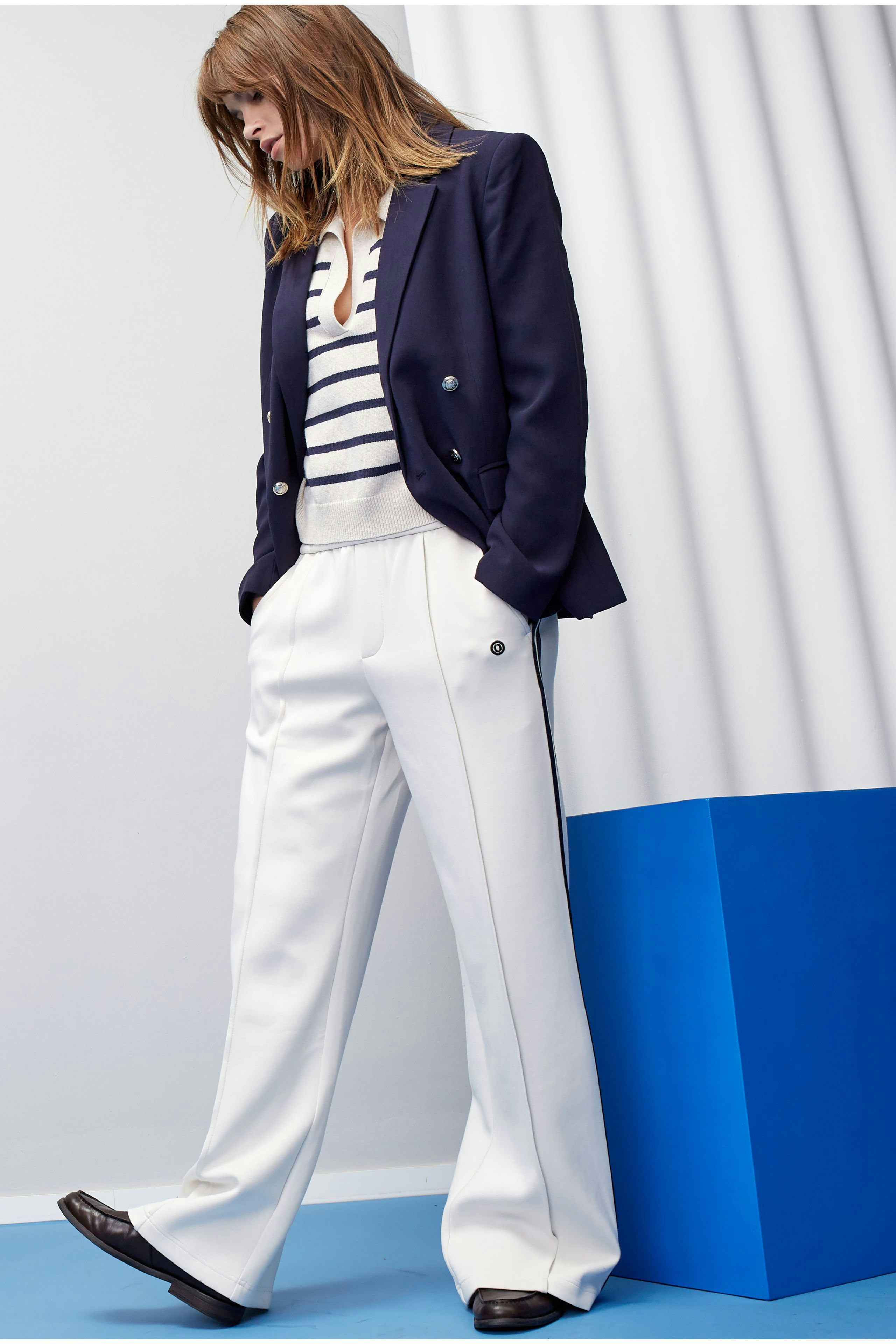 Eleganter Damen-Blazer in Navy, kombiniert mit gestreiftem Oberteil und weißen Hosen.