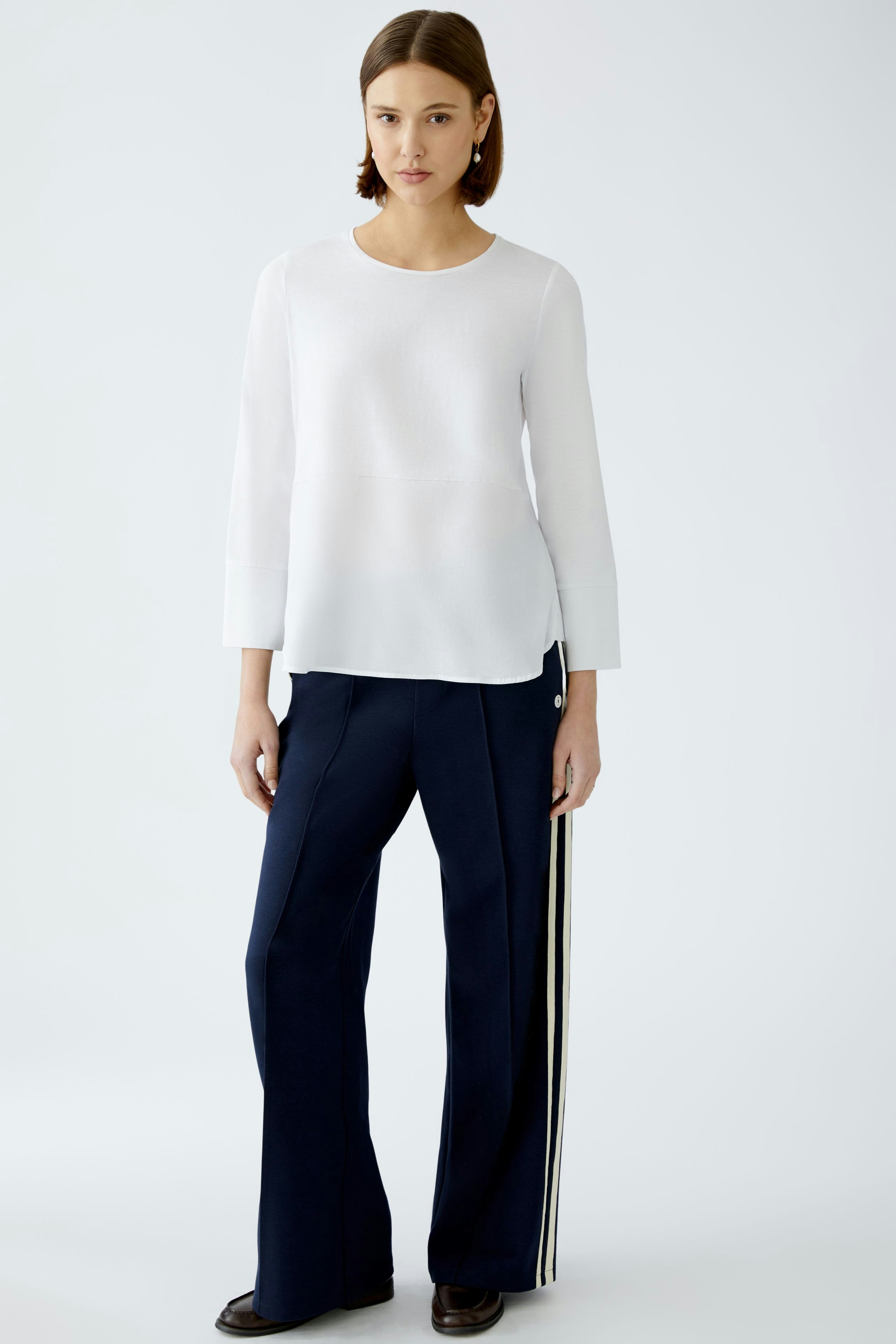 Elegant women's blouse shirt in white, paired with navy trousers, showcasing a modern style.