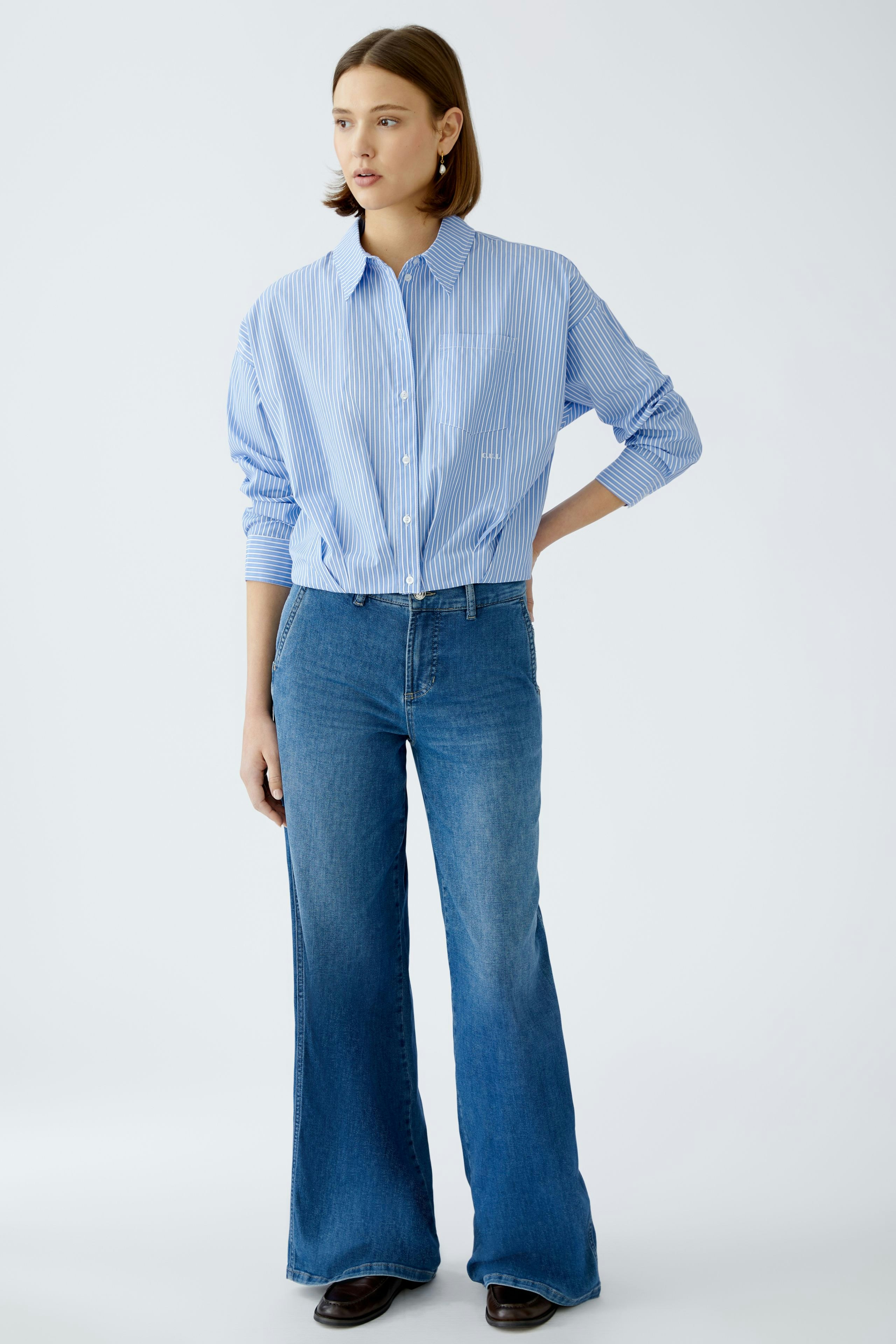 Moderne Damen-Bluse: Frau in gestreifter Bluse mit lässigem Schnitt und eleganten Details.