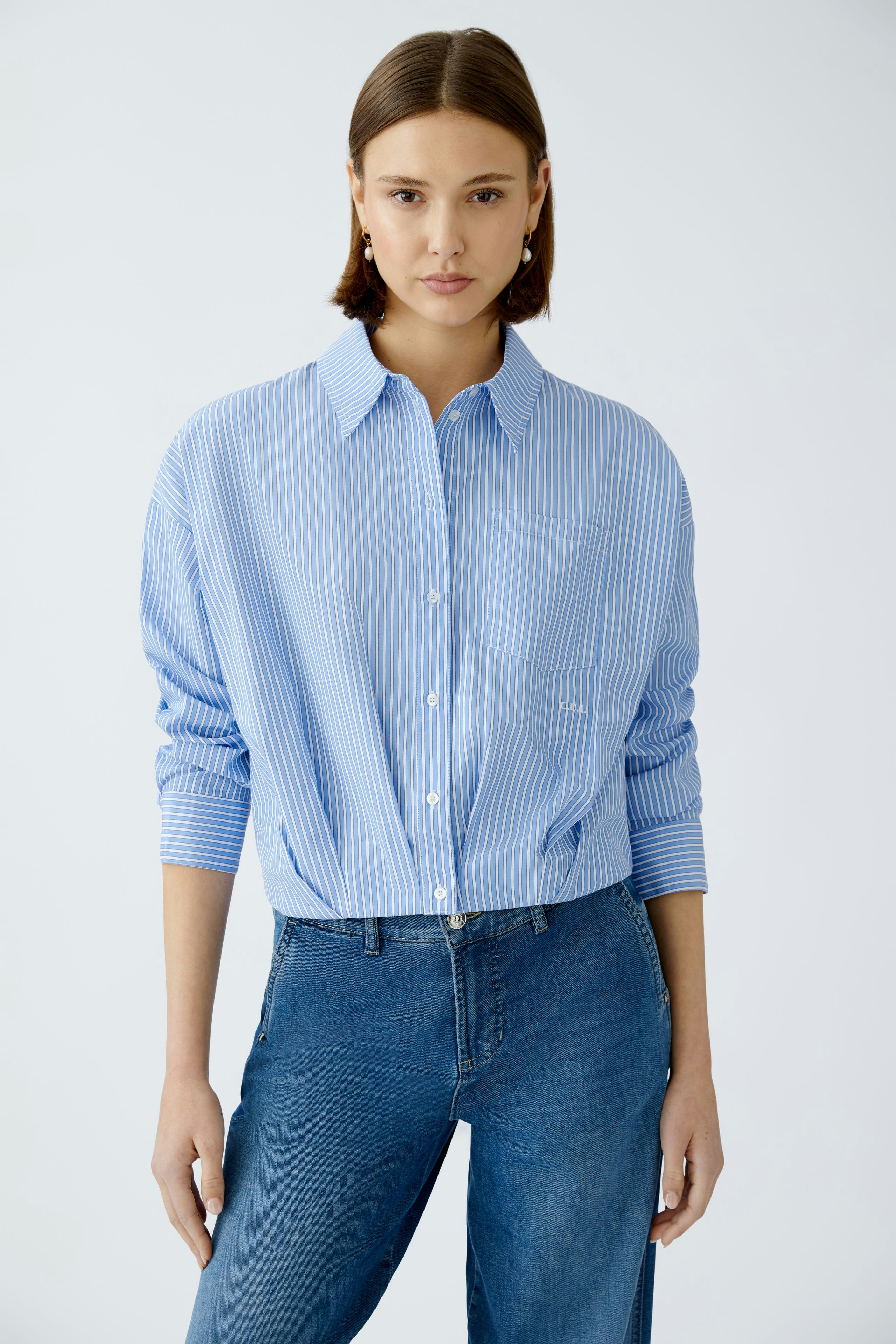 Moderne Damen-Bluse: Frau in blauer gestreifter Bluse mit lässigem Schnitt und Knopfleiste.