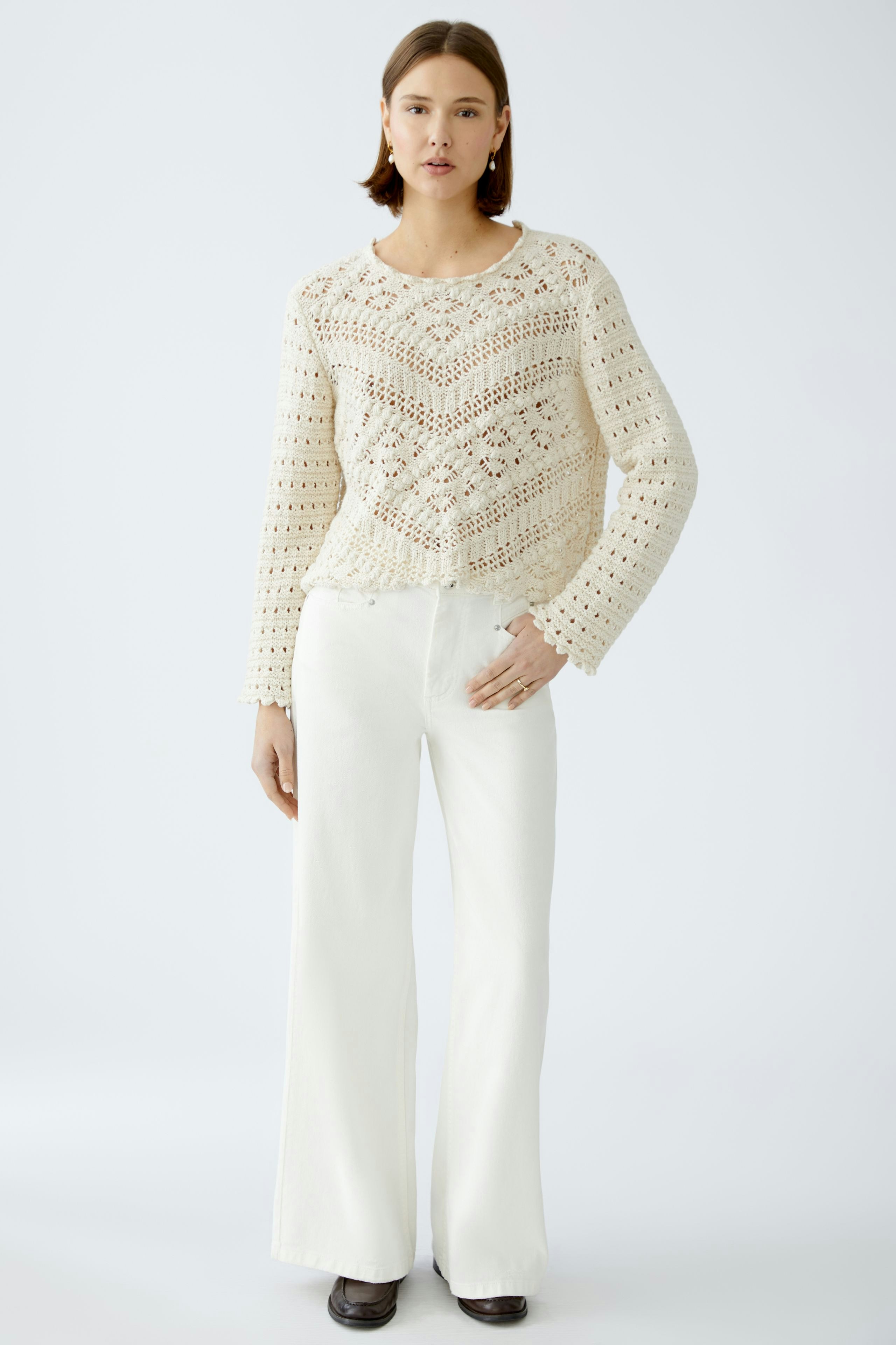 Stylish women's pullover: A woman in a cream crochet pullover paired with white wide-leg pants.