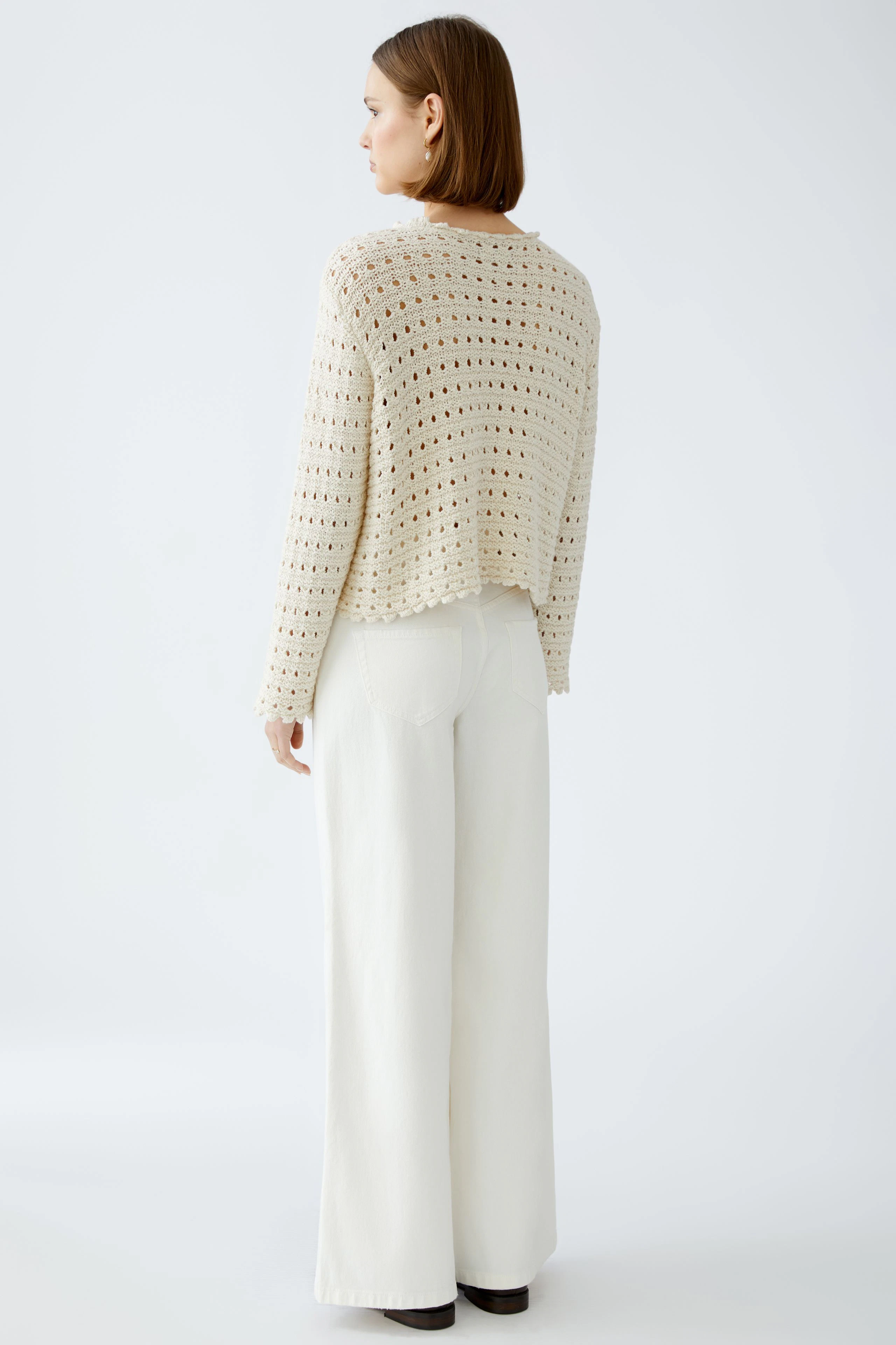 Stylish women's pullover: A woman in a light, open-knit pullover paired with wide-leg pants.