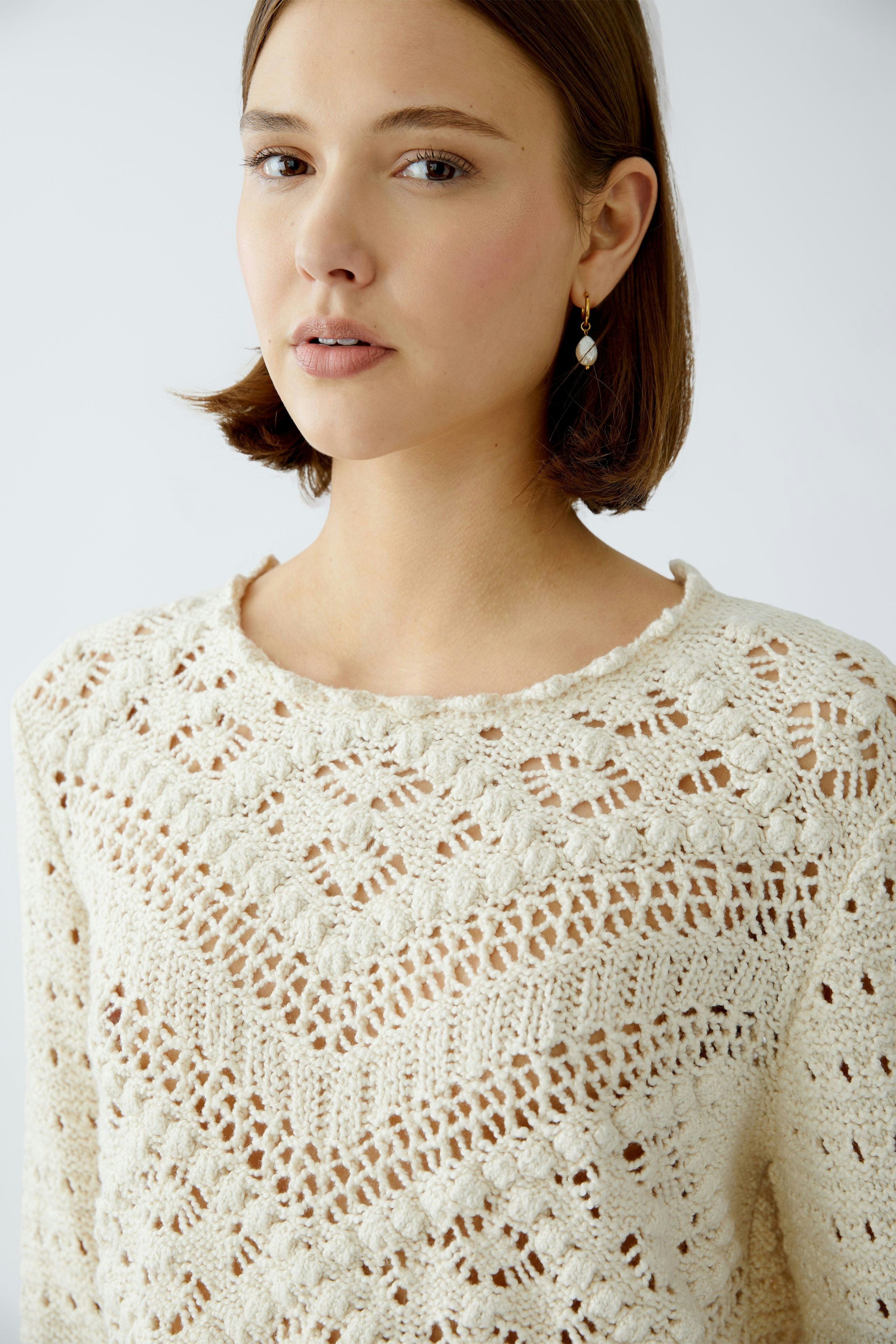 Stylish women's pullover: A woman in a cream knitted pullover with intricate patterns, exuding elegance.