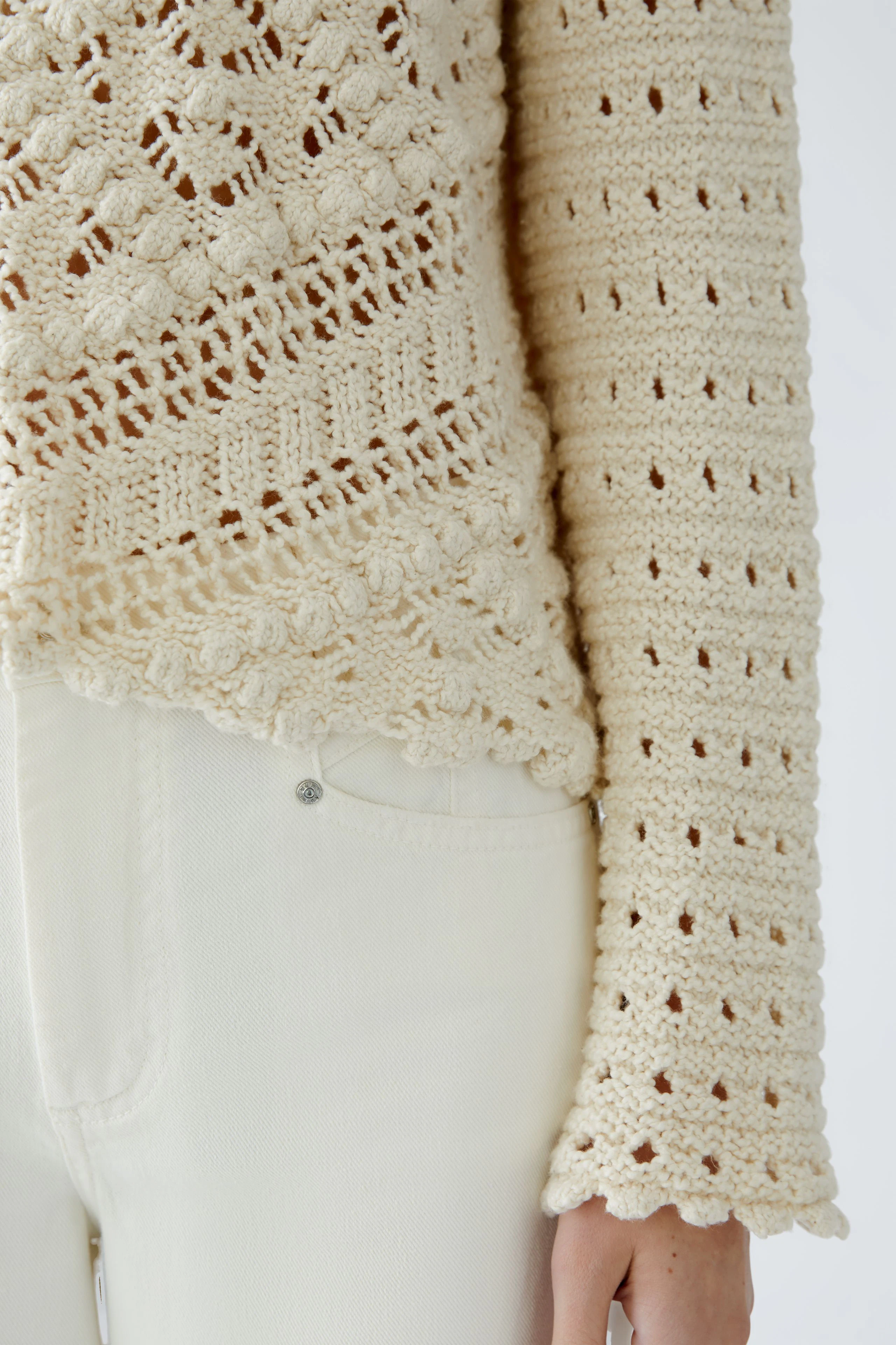Stylish women's pullover: Close-up of a cream crochet pullover with intricate patterns and long sleeves.