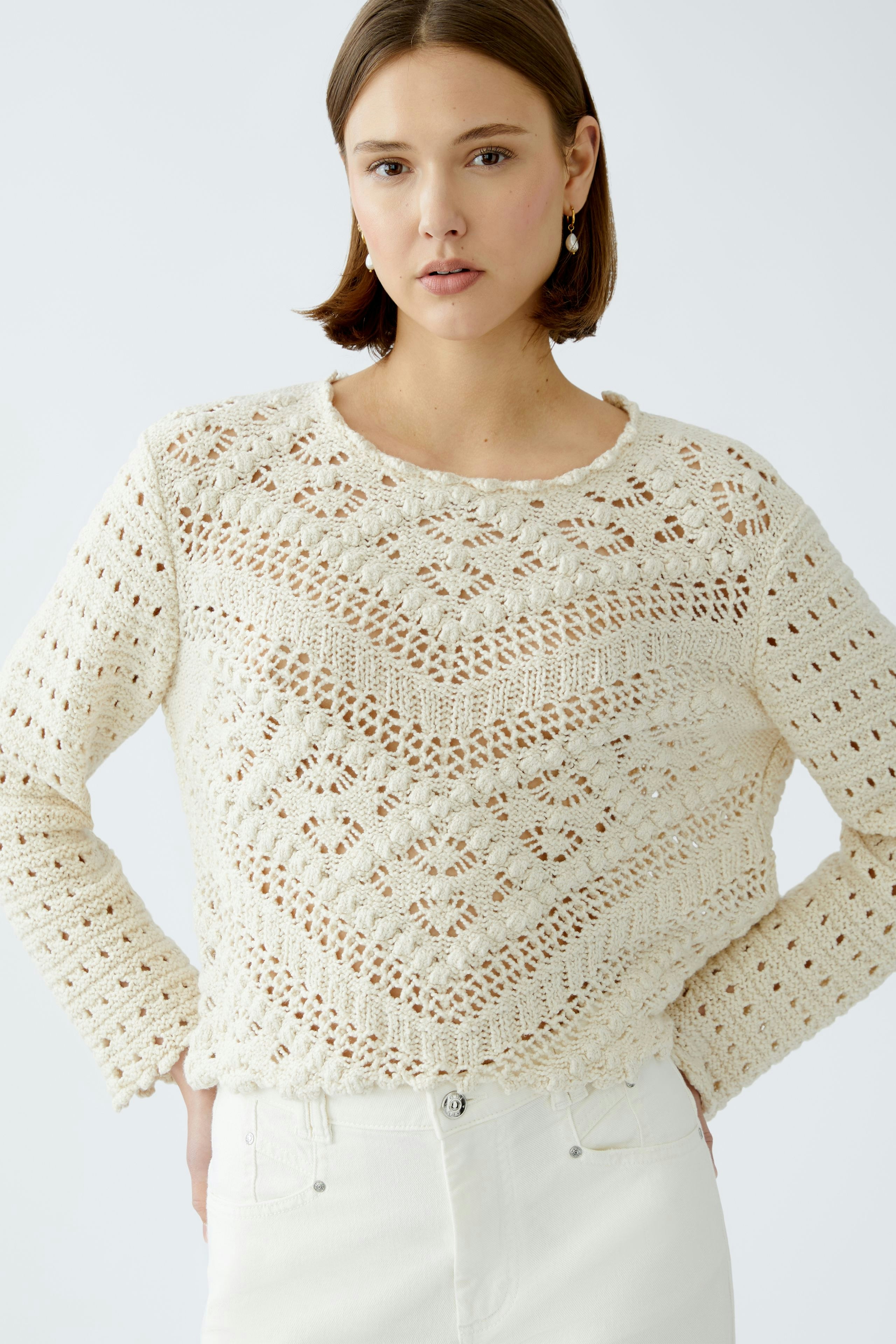 Stylish women's pullover: A woman in a cream knitted pullover with intricate patterns.