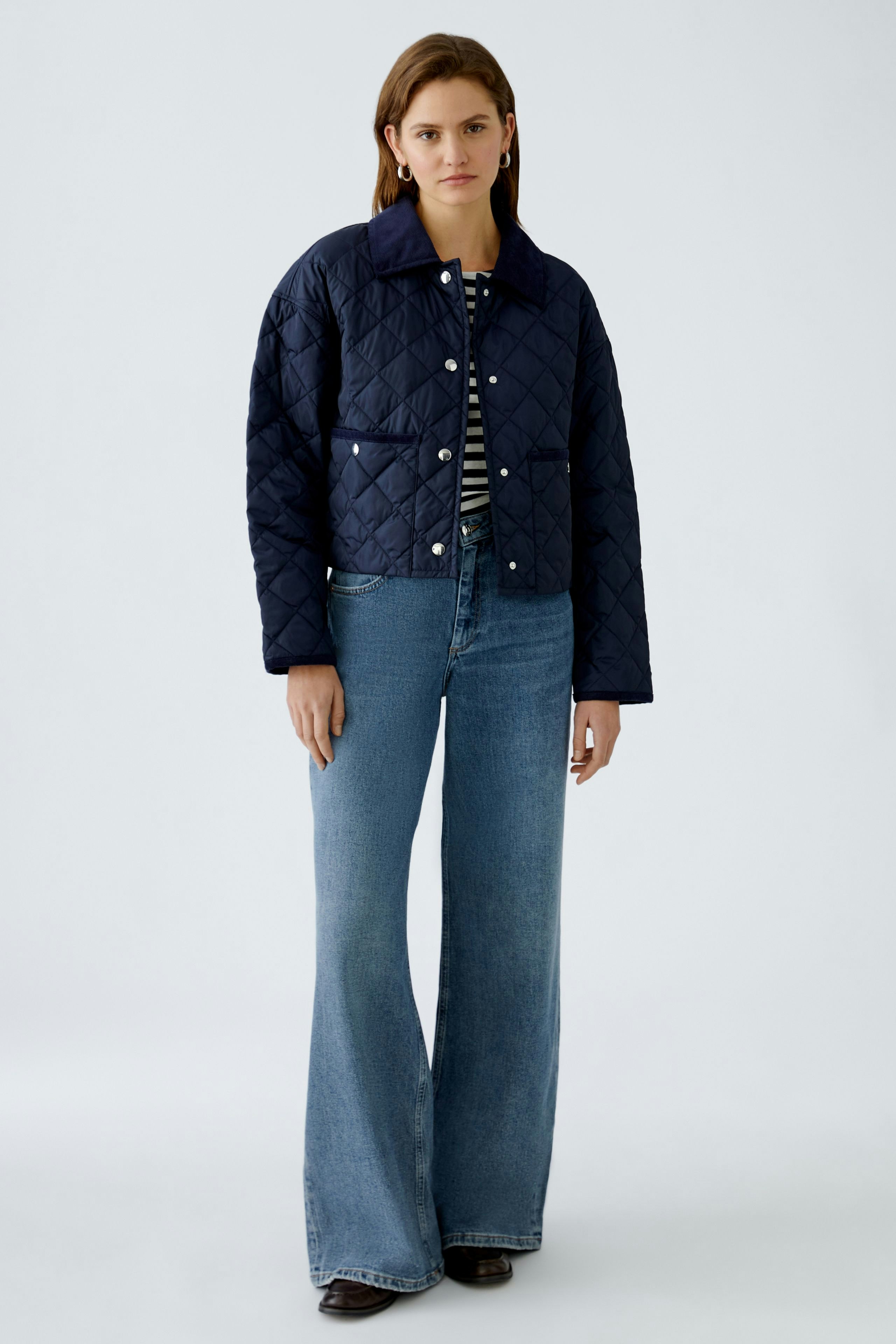 Stylish outdoor jacket: A woman in a navy quilted jacket paired with flared jeans.