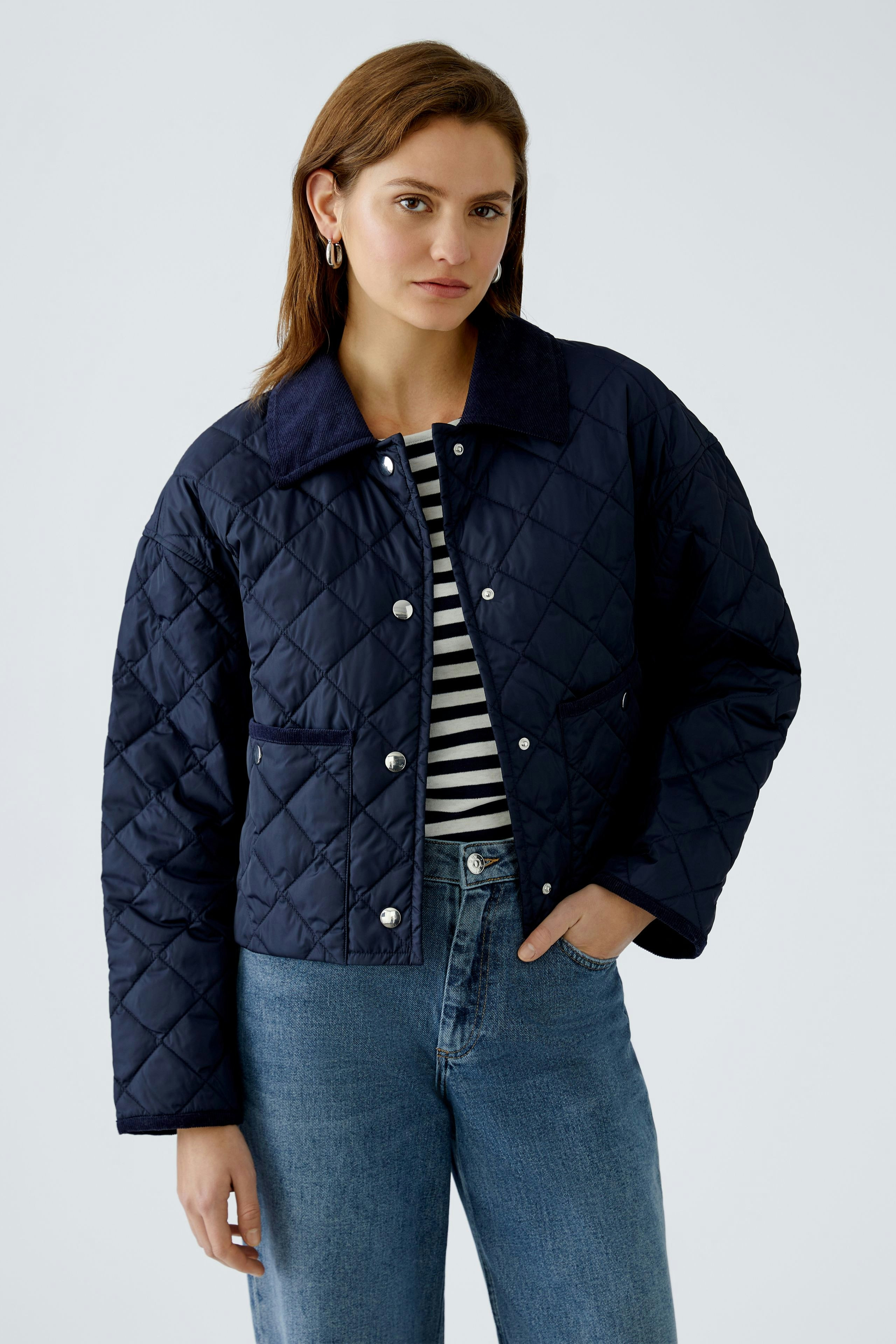 Stylish outdoor jacket: Woman in a navy quilted jacket with a classic collar and striped top.