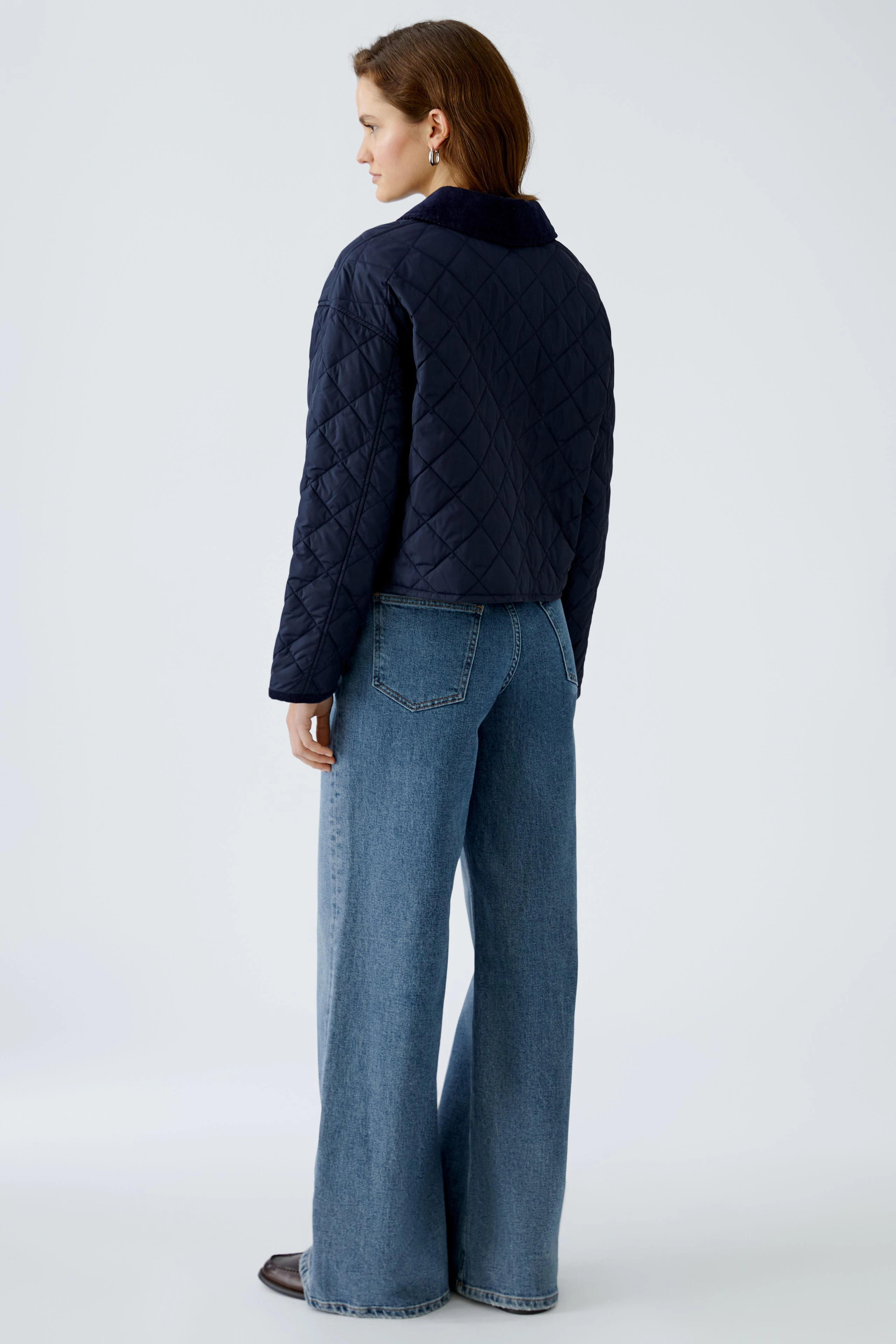 Stylish outdoor jacket: Woman in a navy quilted jacket paired with wide-leg jeans.