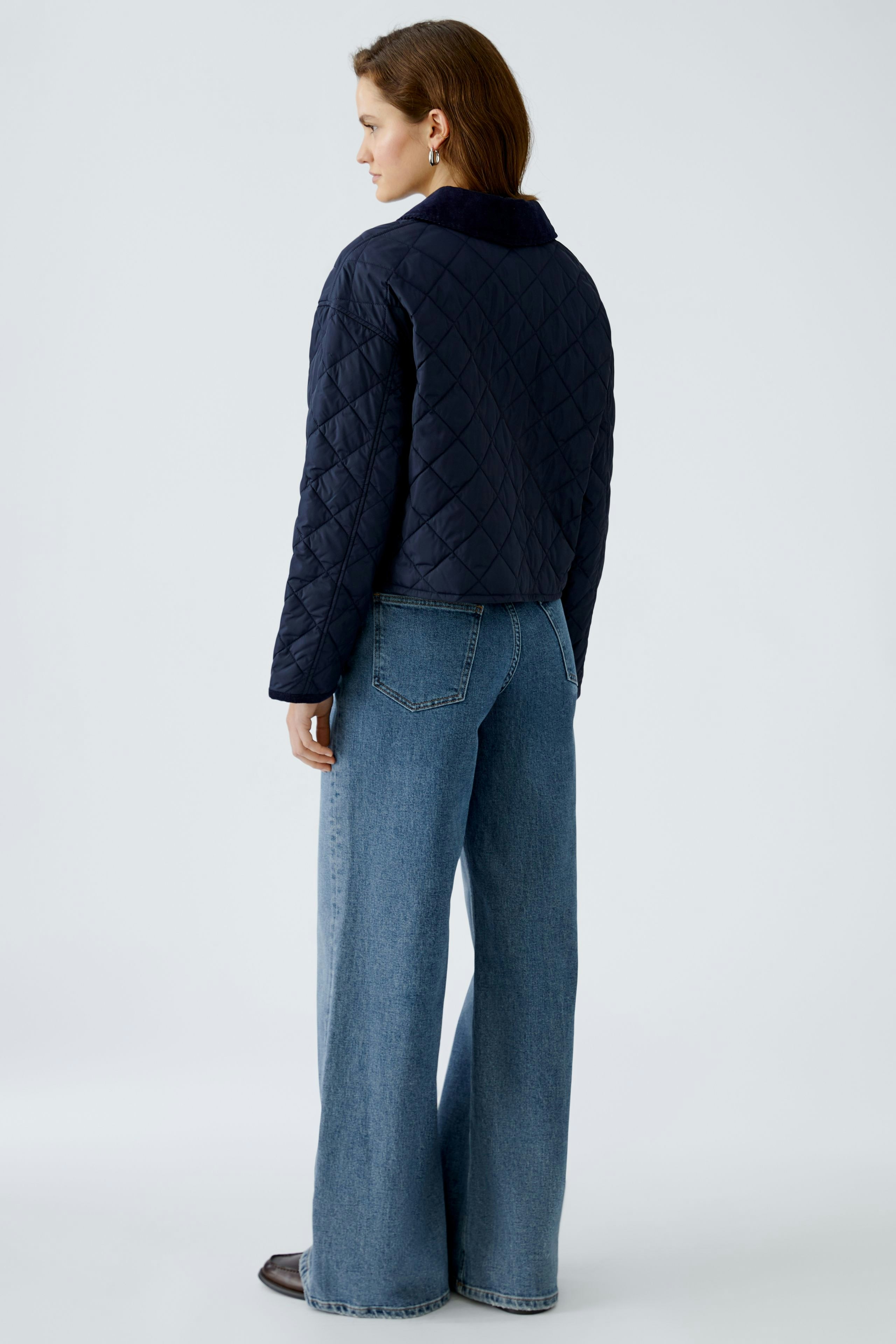 Stylish outdoor jacket: Woman in a navy quilted jacket paired with wide-leg jeans.