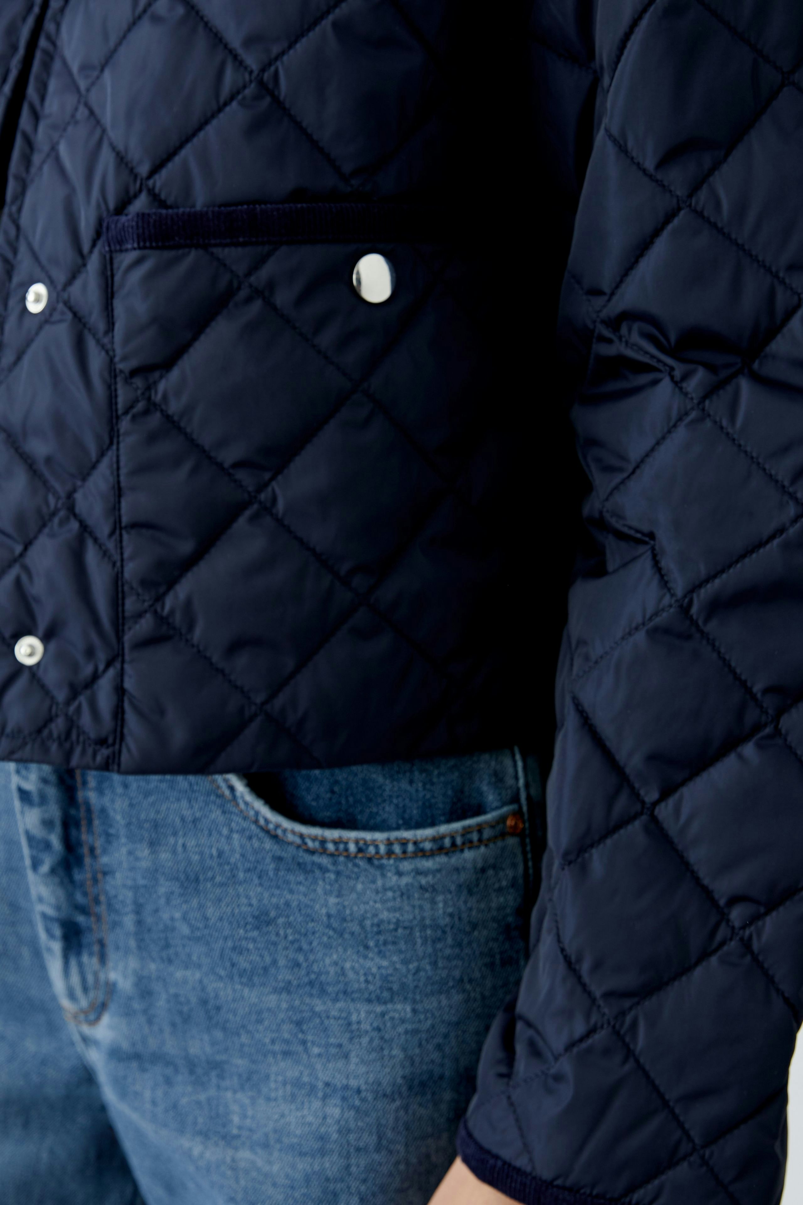 Stylish outdoor jacket: A woman in a navy quilted jacket with a pocket, perfect for outdoor activities.