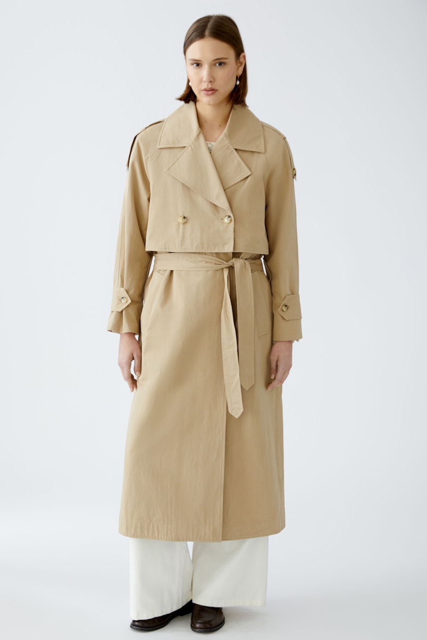 Stylish trench coat: A woman in a beige trench coat with a belted waist and classic double-breasted design.