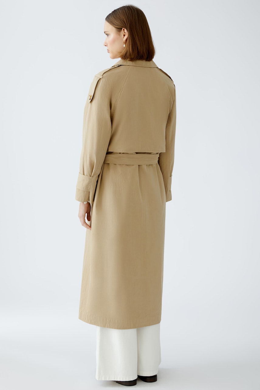 Stylish trench coat: A woman in a beige trench coat with a belted waist and classic design.